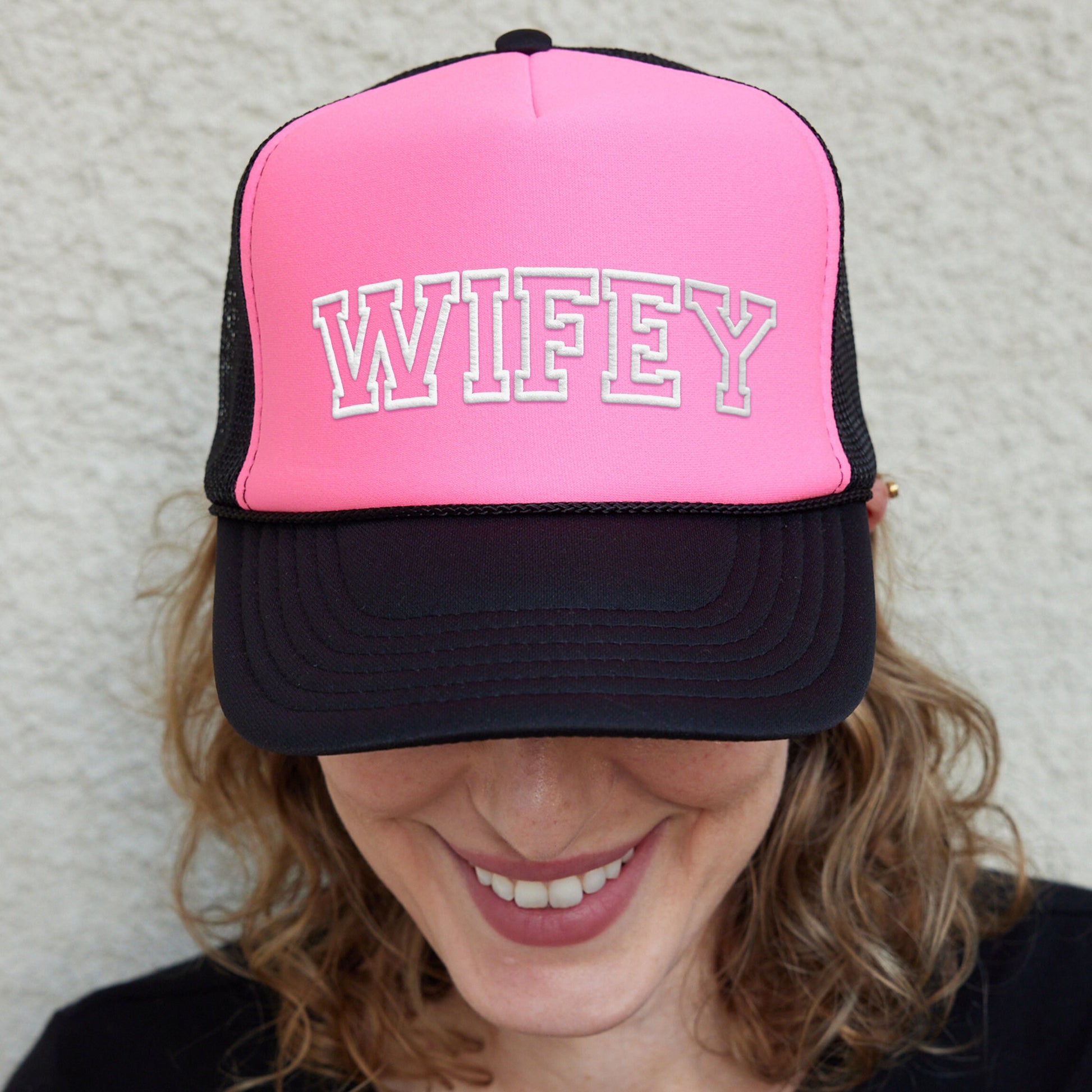 a smiling woman wearing a pink and black hat