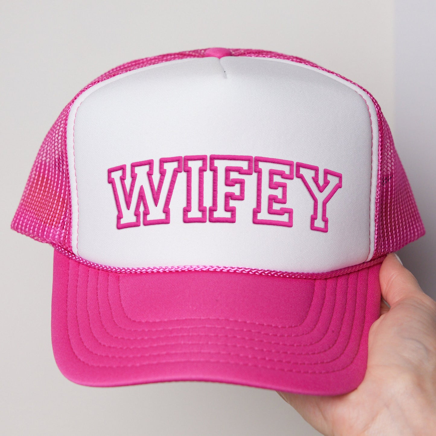 a person holding a pink and white hat