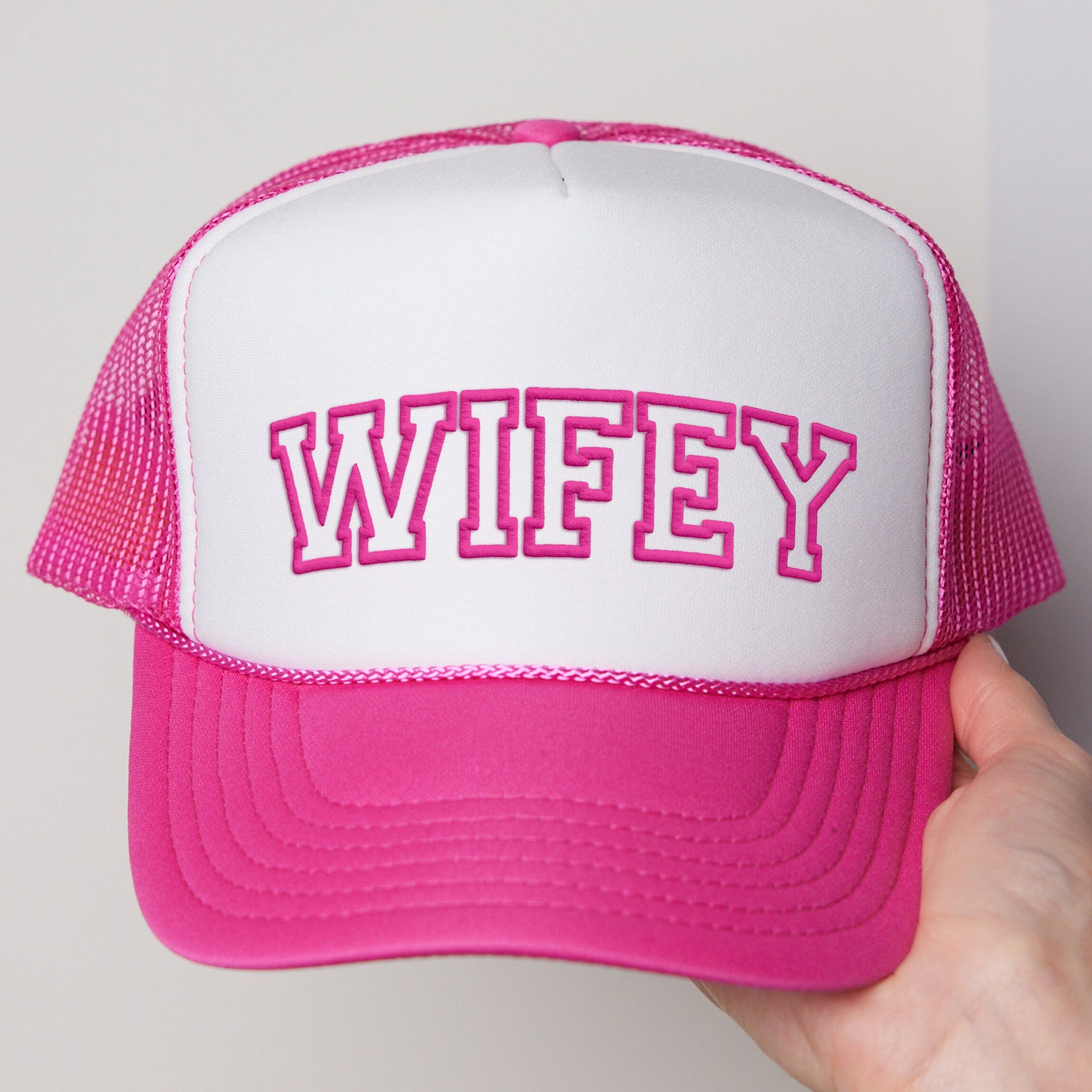 a person holding a pink and white hat