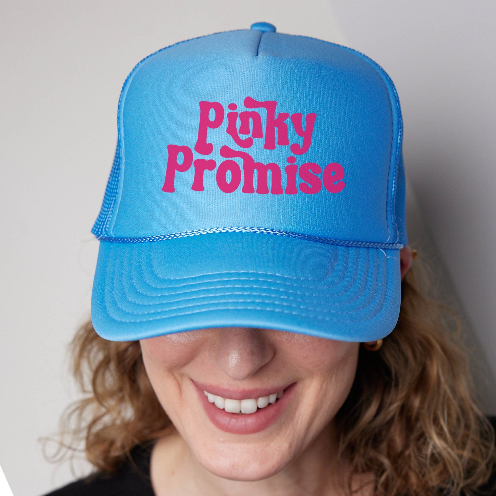 a woman wearing a blue hat with pink writing on it