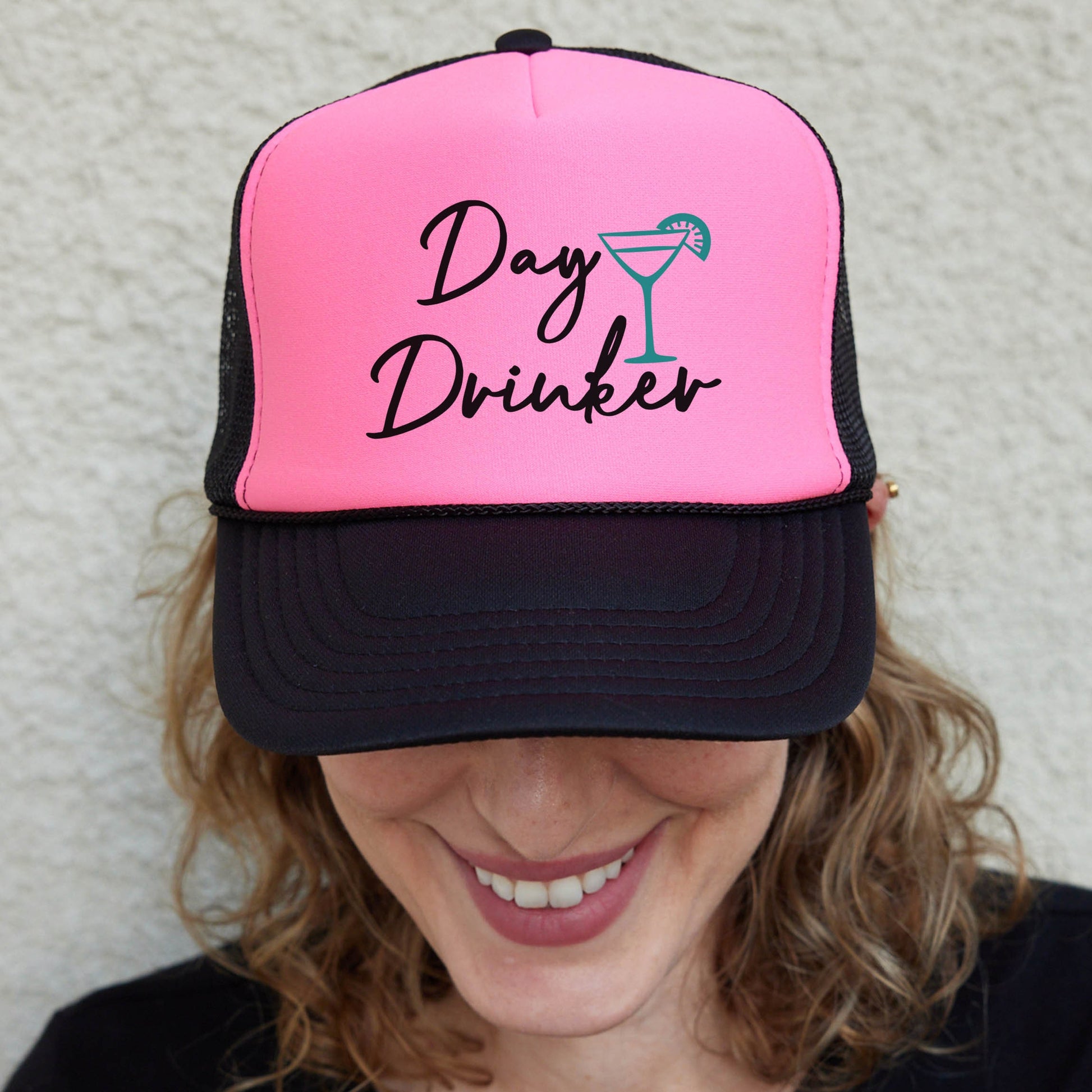 a woman wearing a pink and black hat with the words day drinker on it