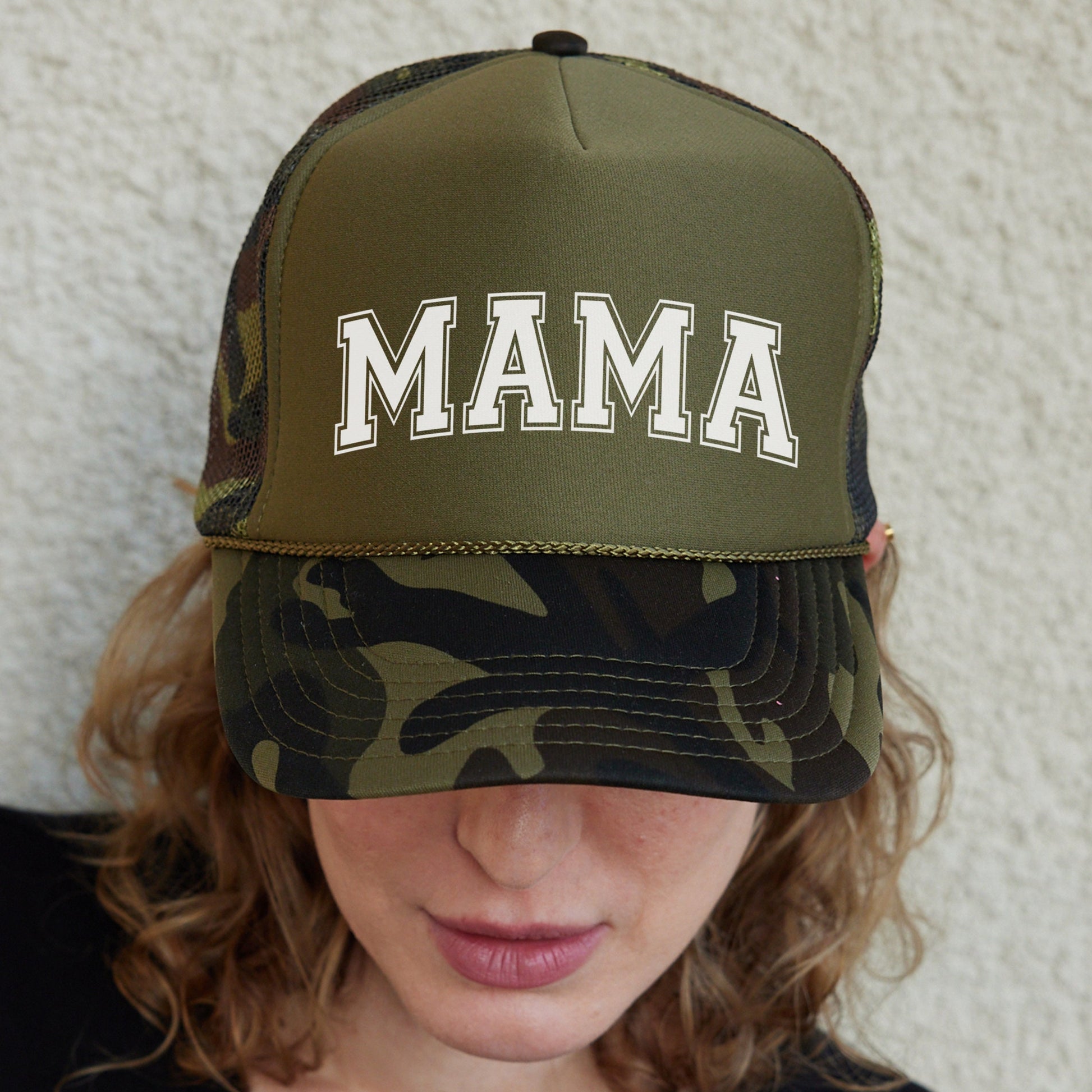 a woman wearing a camo hat with the word mama on it