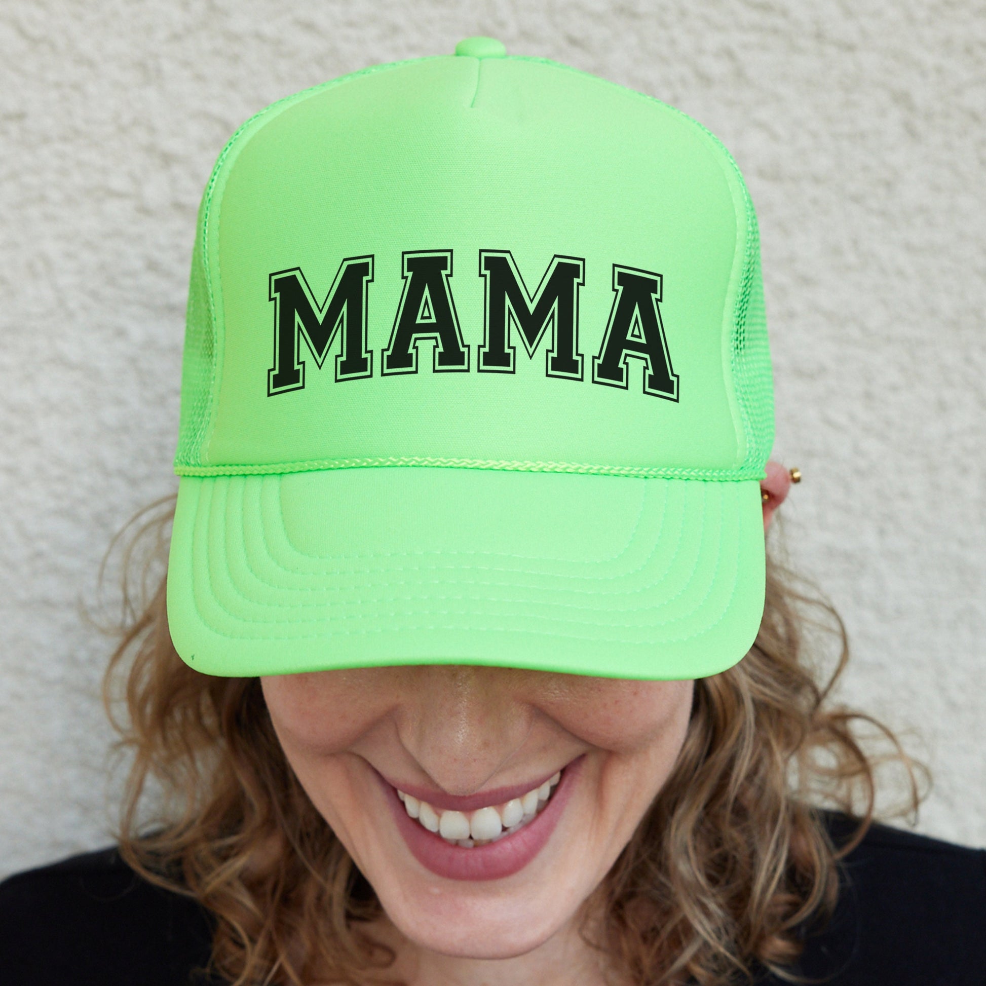 a woman wearing a neon green hat with the word mama on it