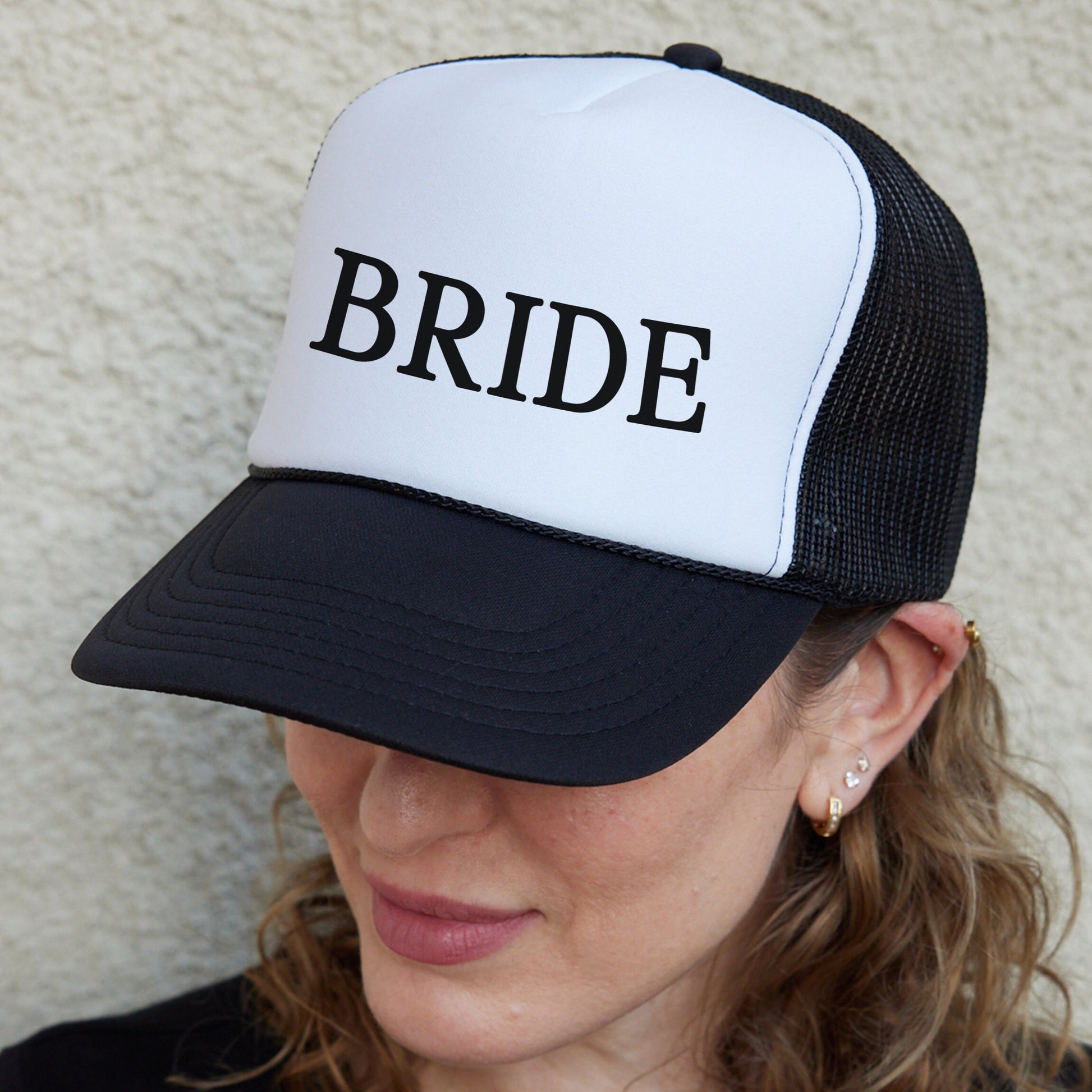 a woman wearing a black and white hat with the word bride on it
