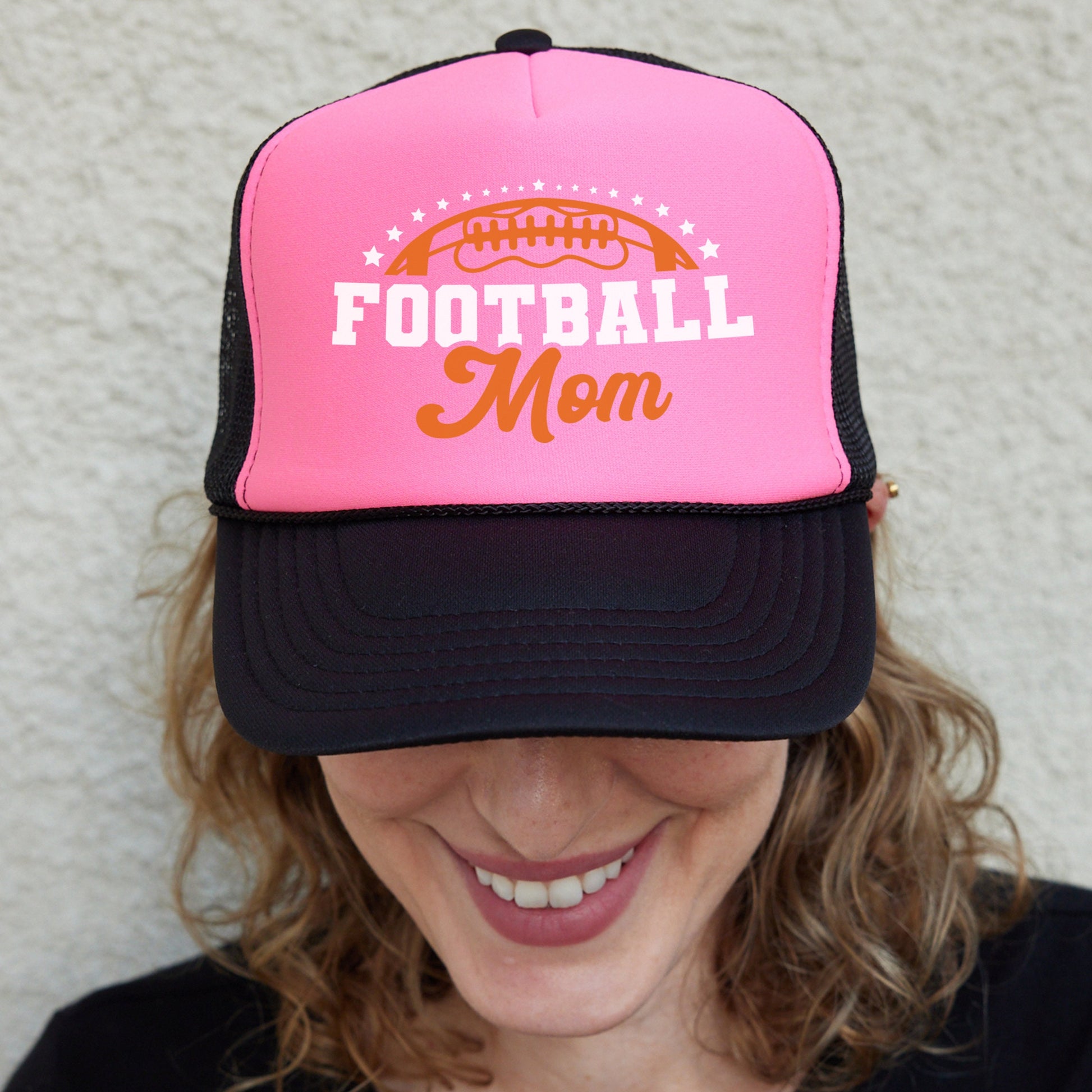 a woman wearing a pink and black football mom hat