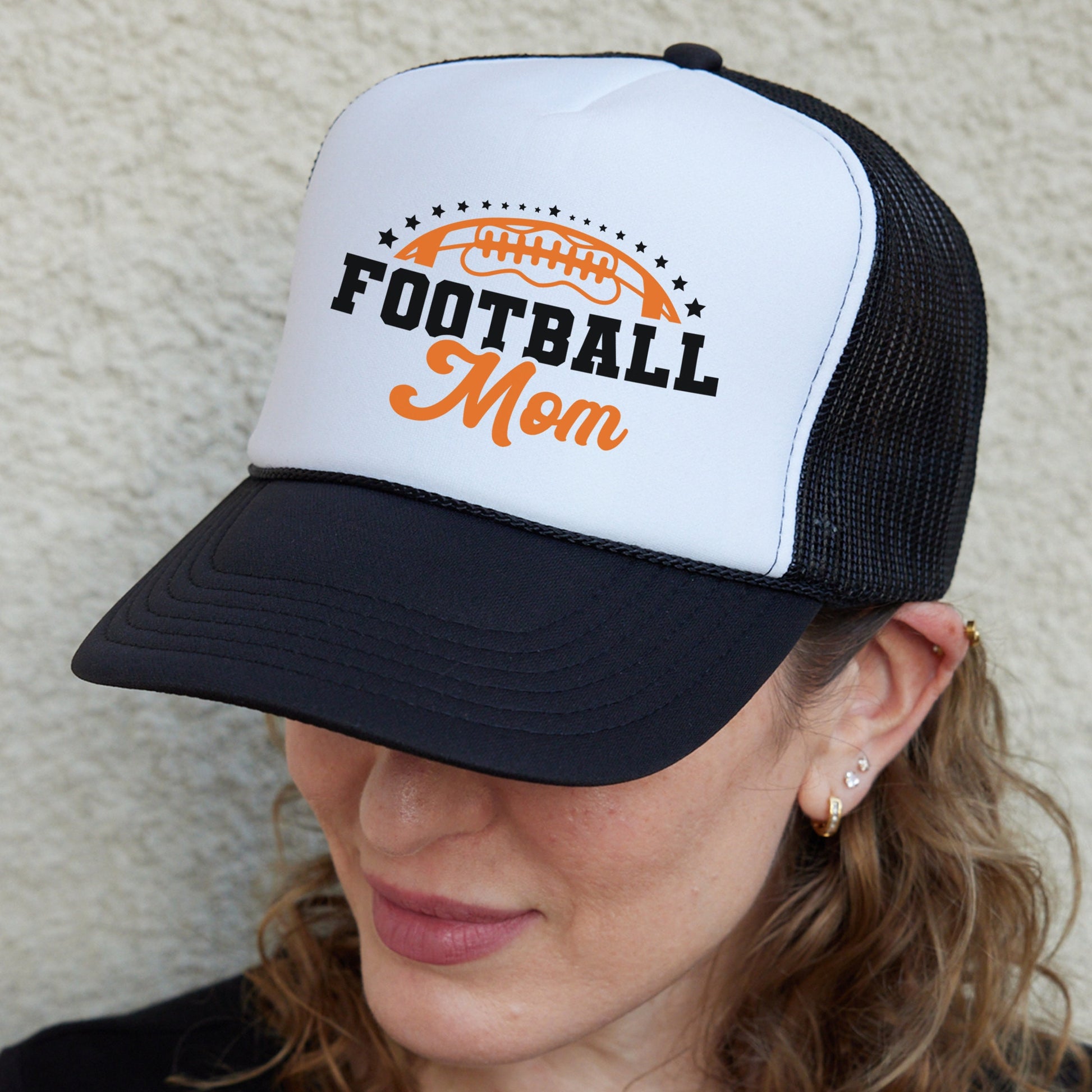 a woman wearing a football mom trucker hat
