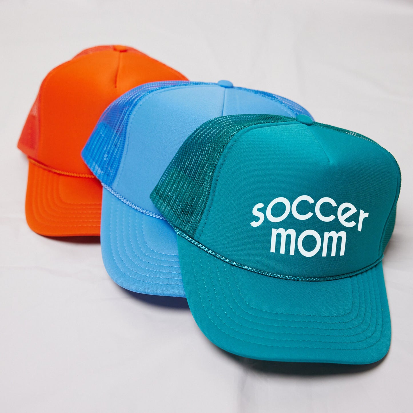 three different colored hats with the word soccer mom on them