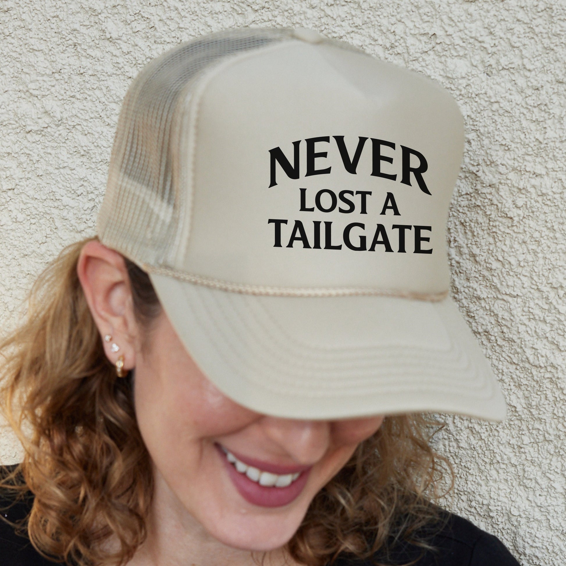 a woman wearing a hat that says never lost a tailgate