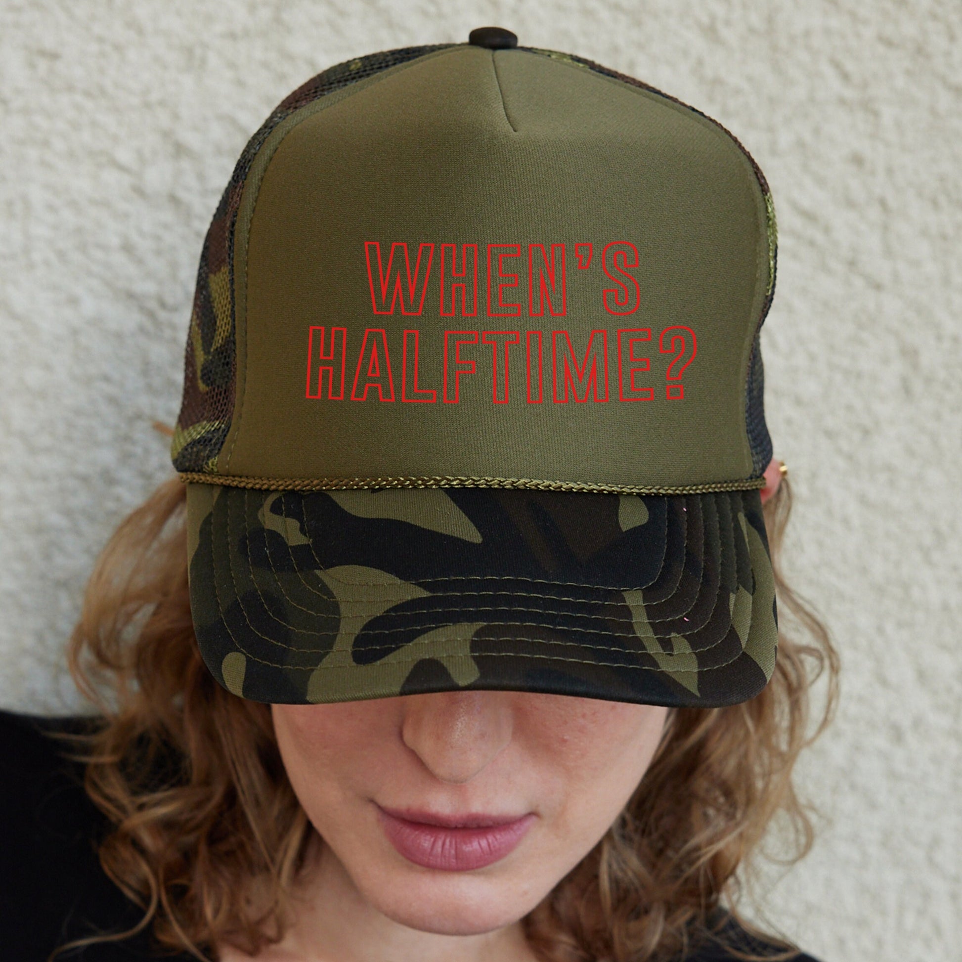 a woman wearing a camo hat with red writing on it