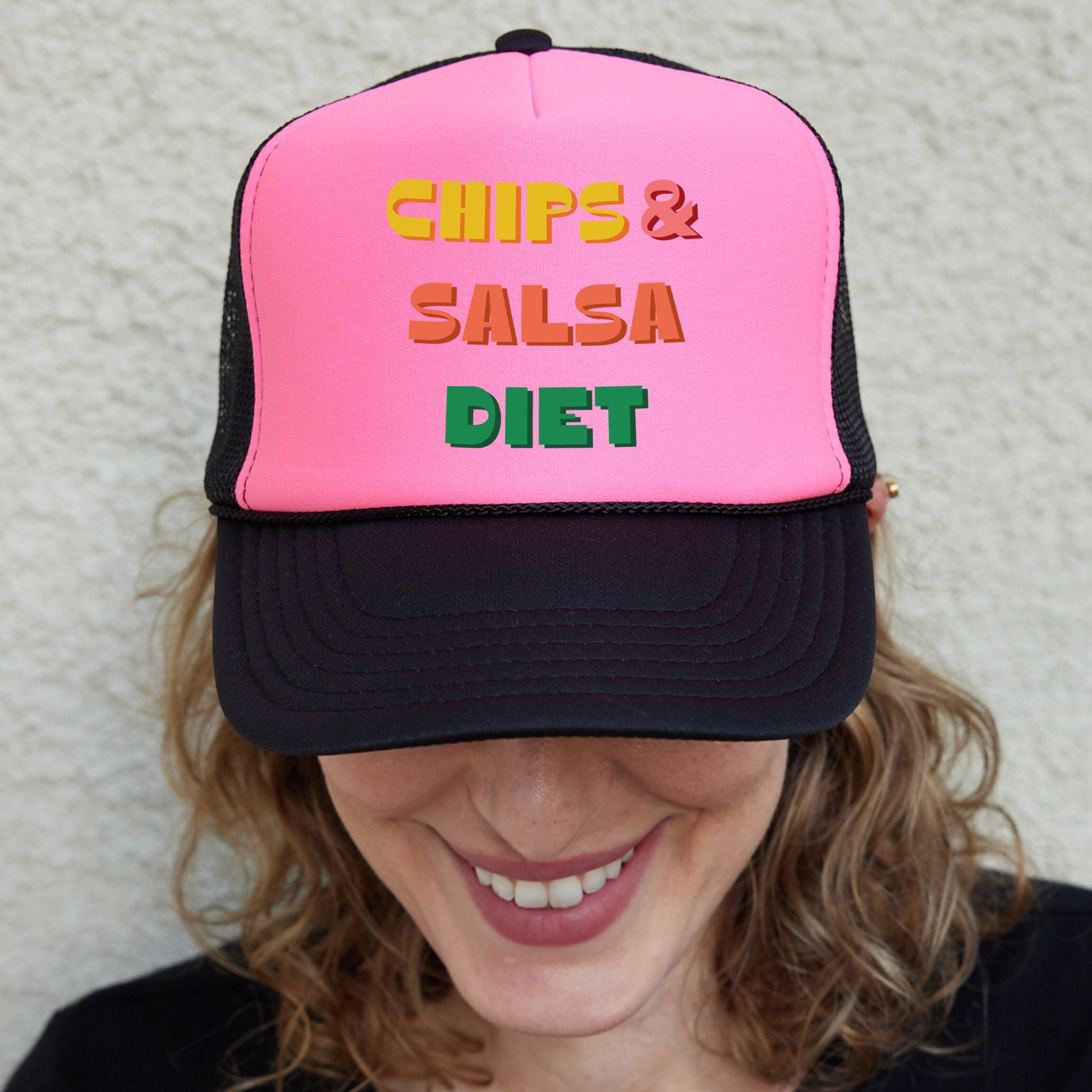 a woman wearing a pink and black trucker hat that says chips and salsa diet