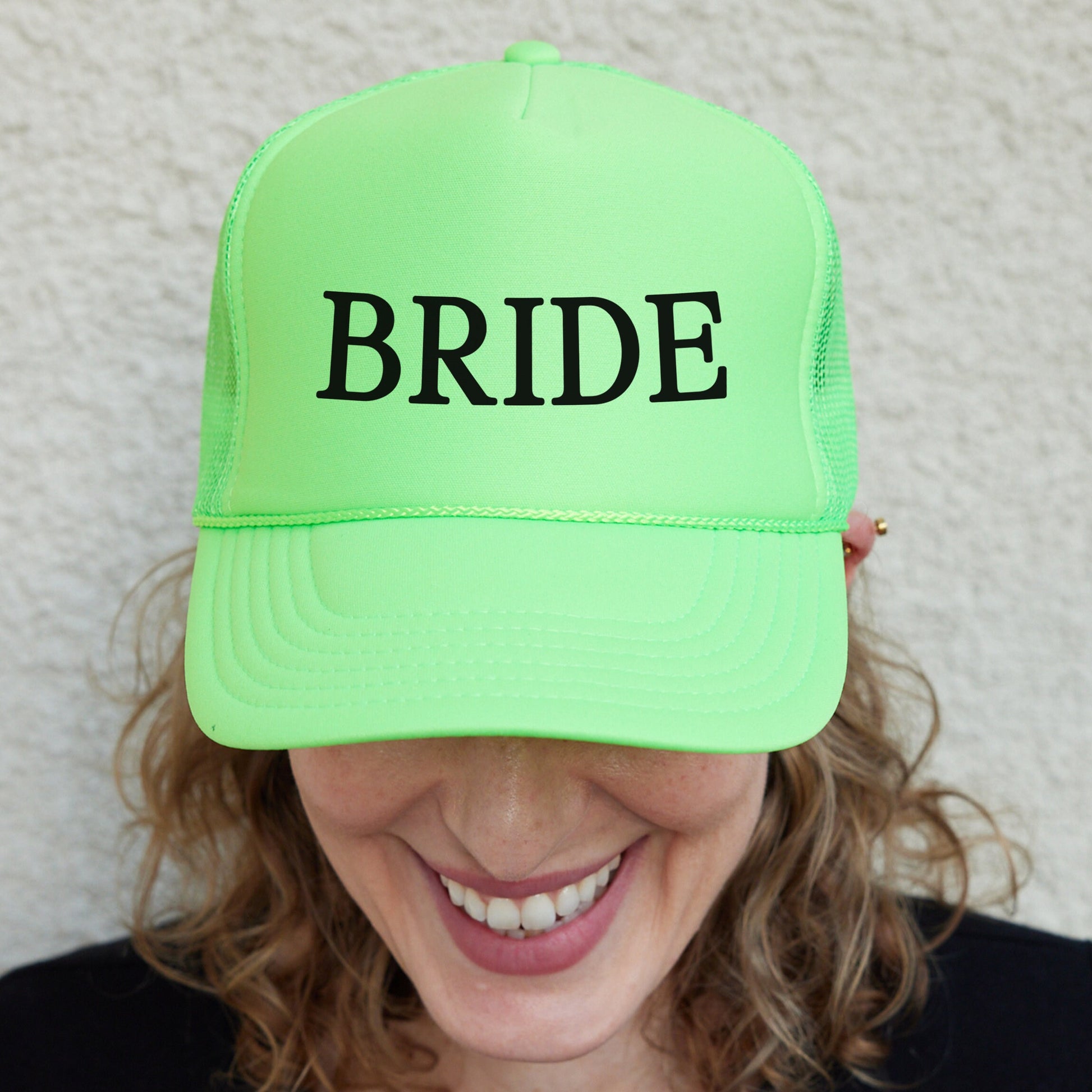 a woman wearing a neon green hat with the word bride printed on it