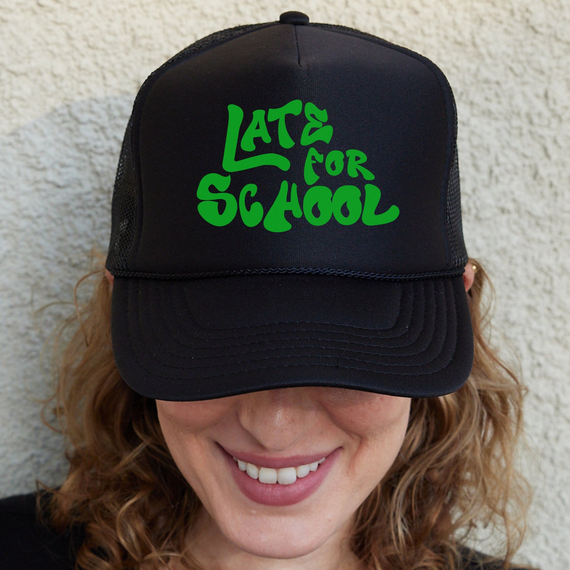 a woman wearing a black hat with green letters on it