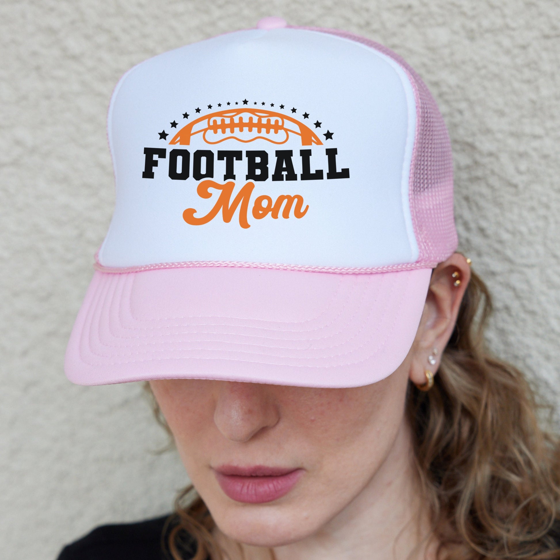 a woman wearing a pink and white football mom hat