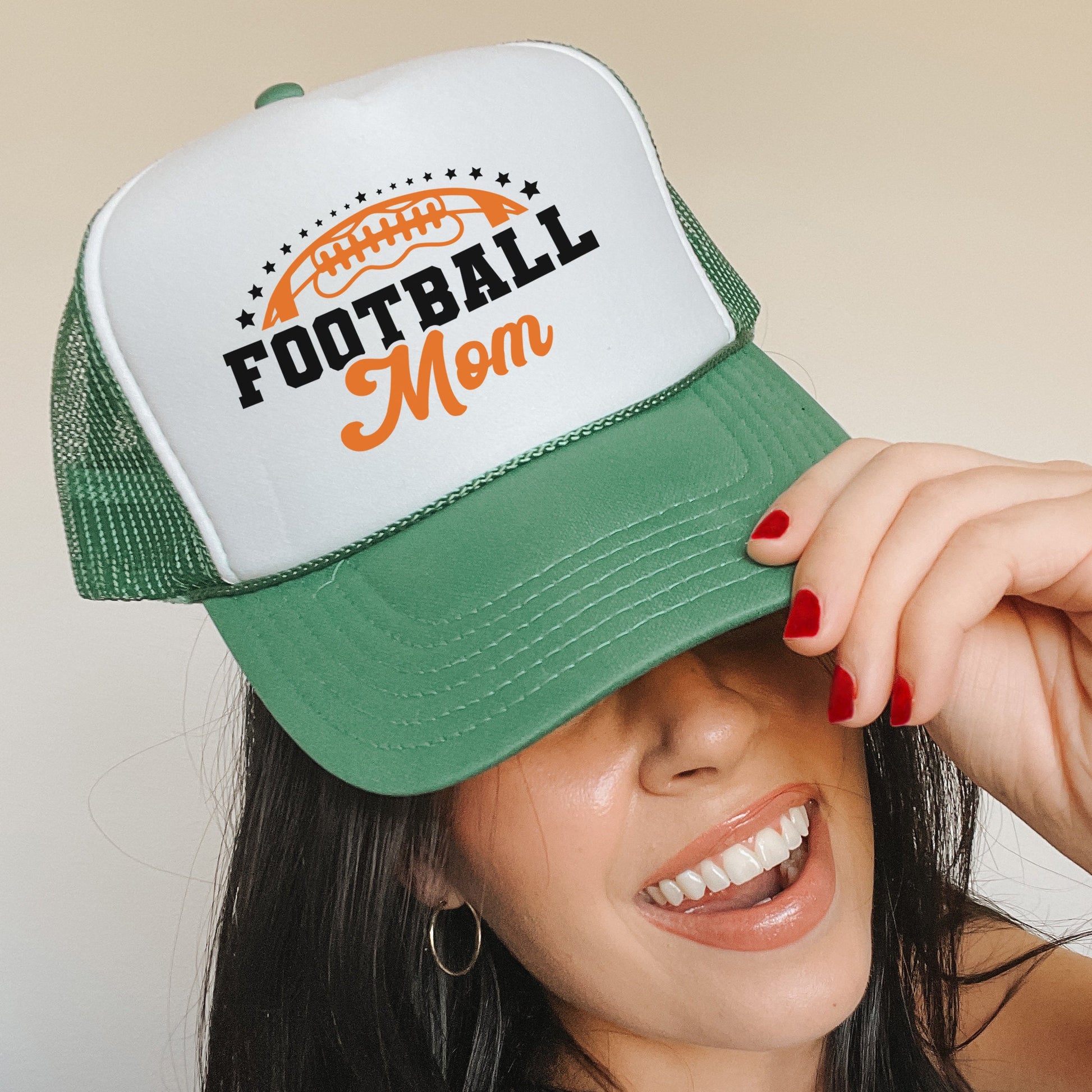 a woman wearing a green and white football mom hat