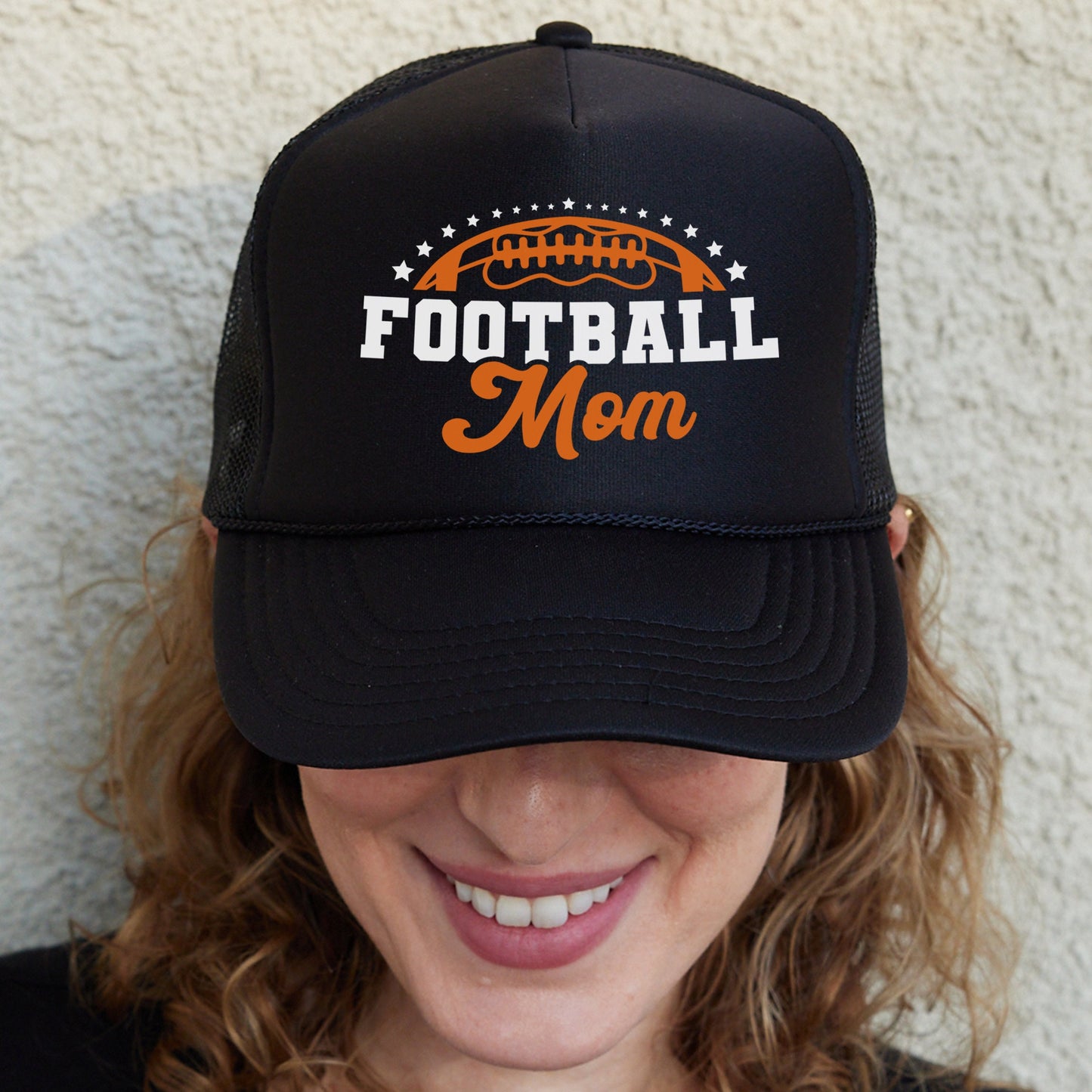 a woman wearing a football mom trucker hat