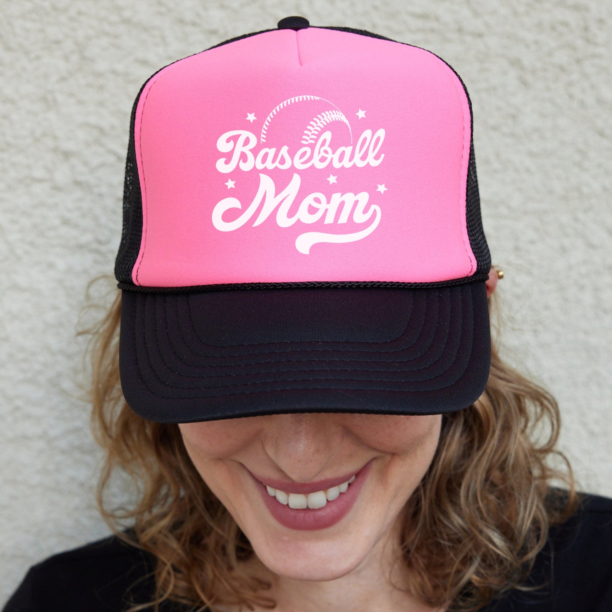 a woman wearing a pink and black baseball mom hat