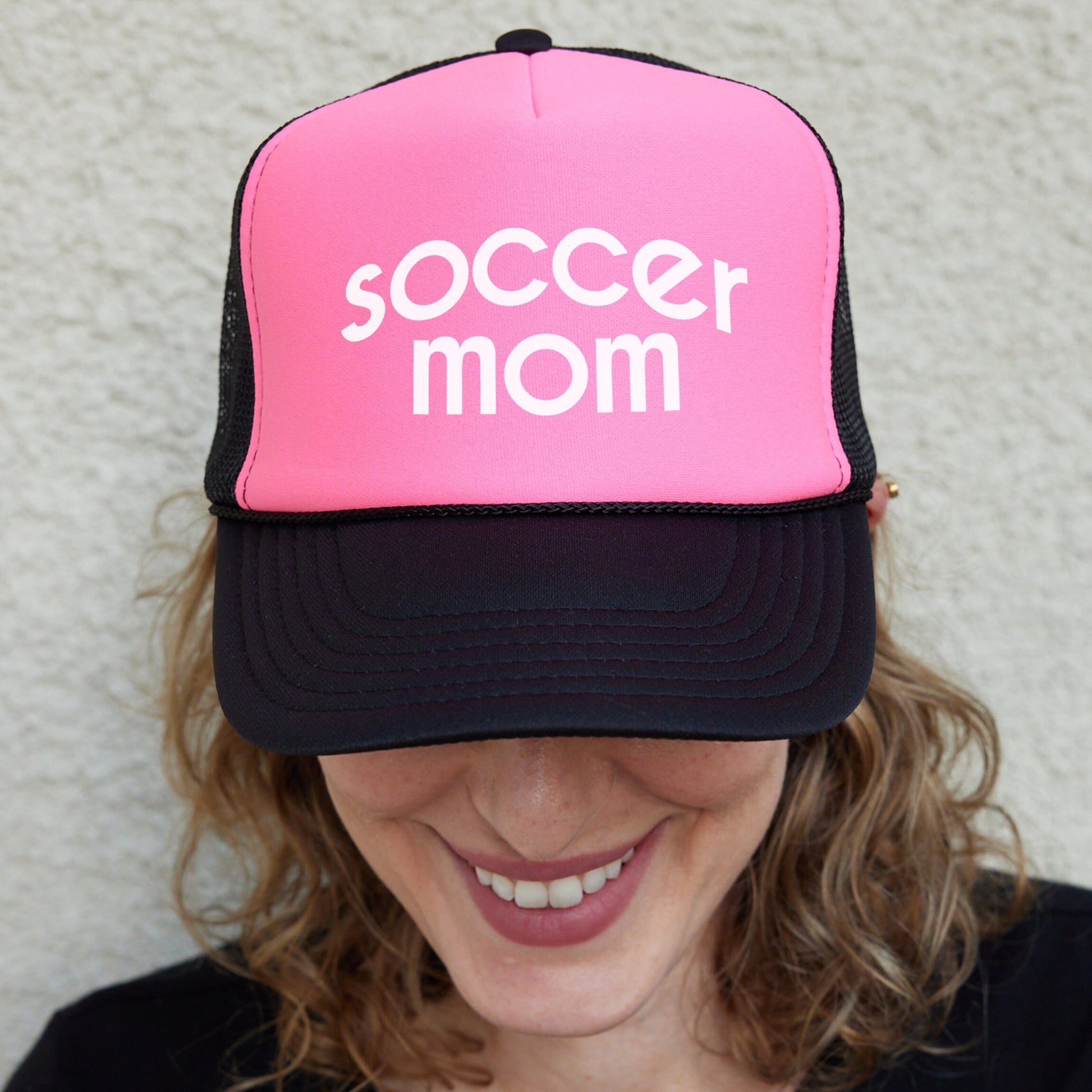a woman wearing a pink and black soccer mom hat