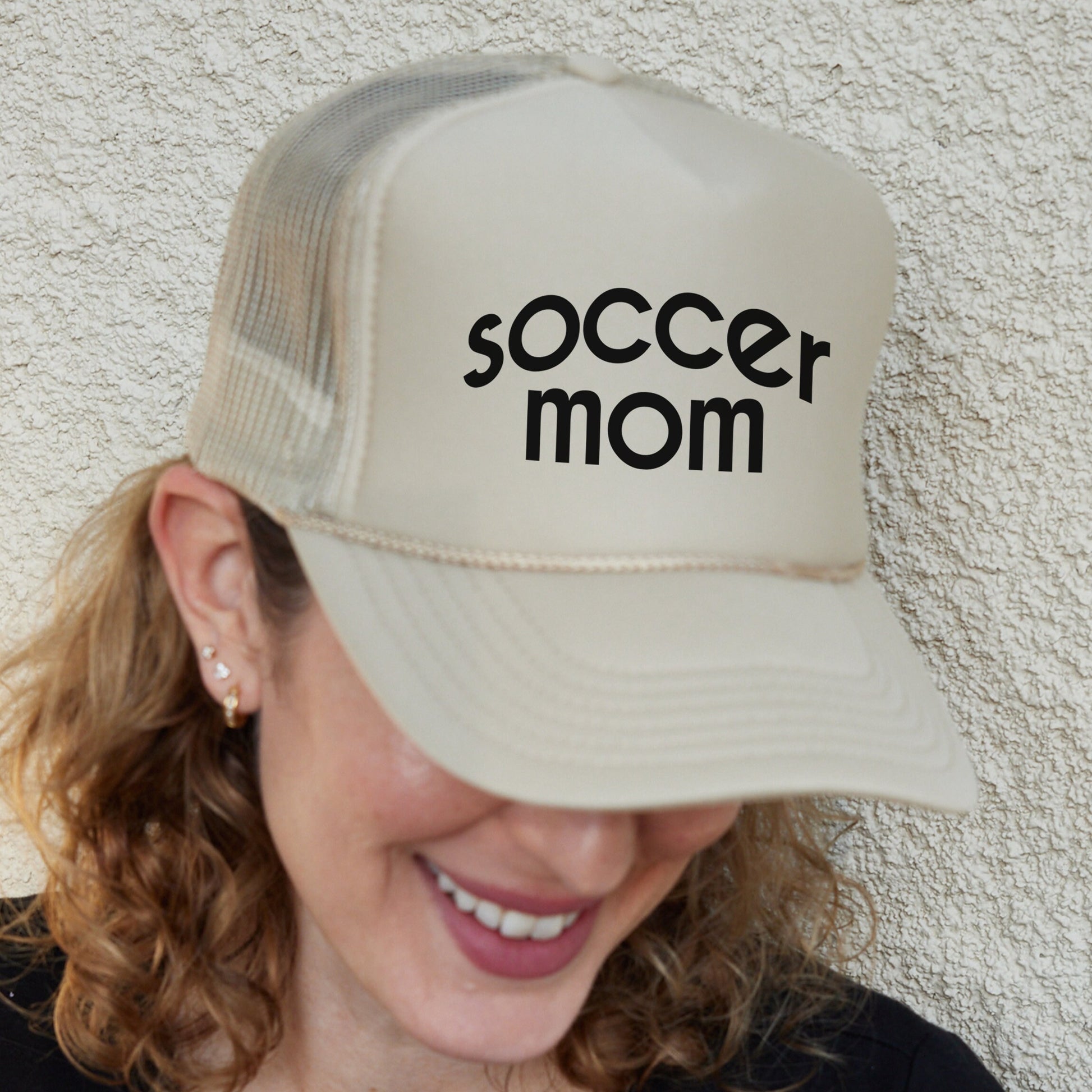 a woman wearing a hat that says soccer mom