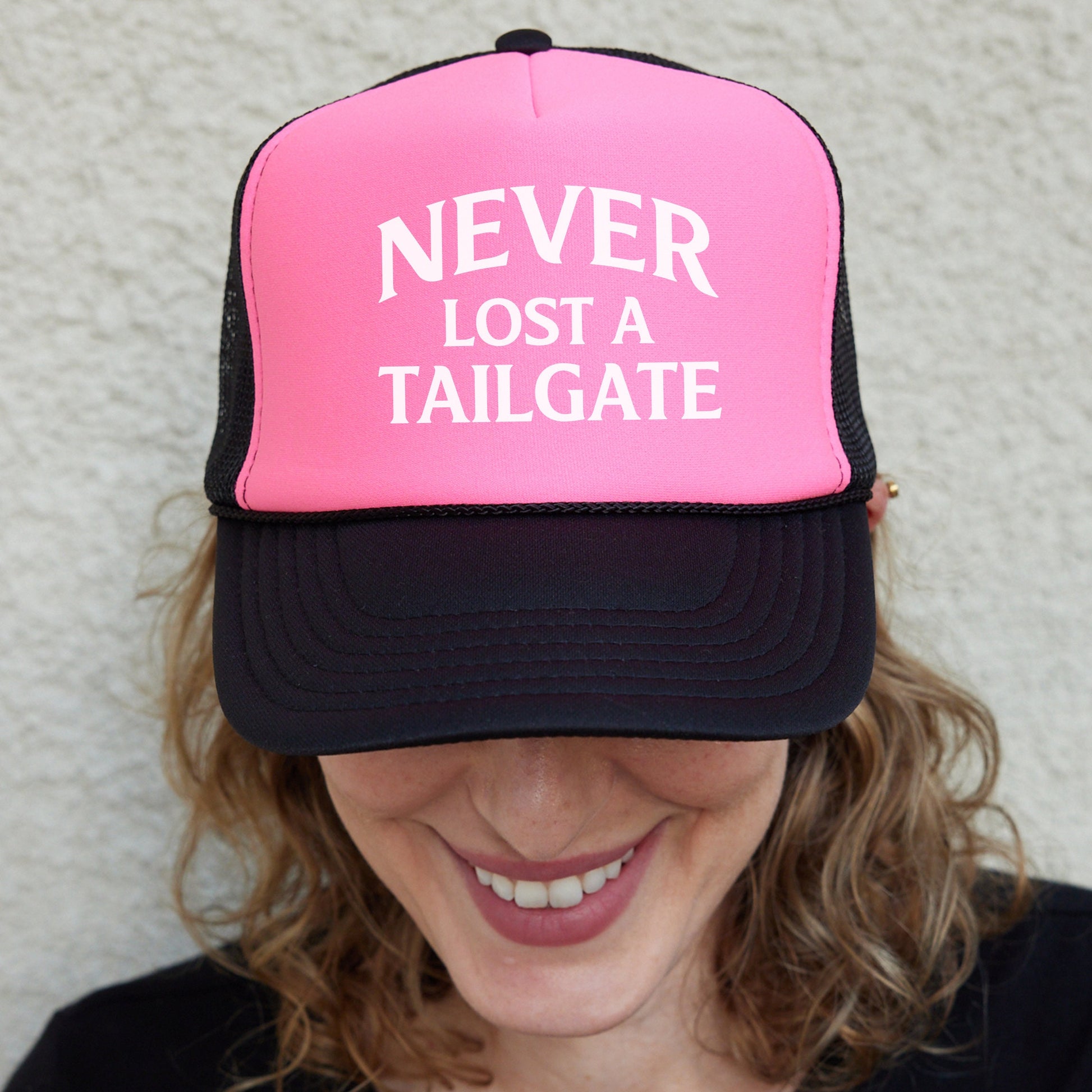 a smiling woman wearing a pink and black trucker hat
