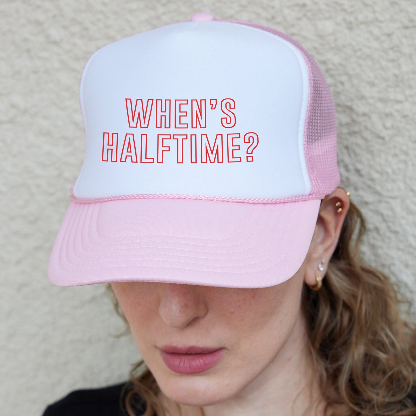 a woman wearing a pink and white hat with the words when&#39;s half time