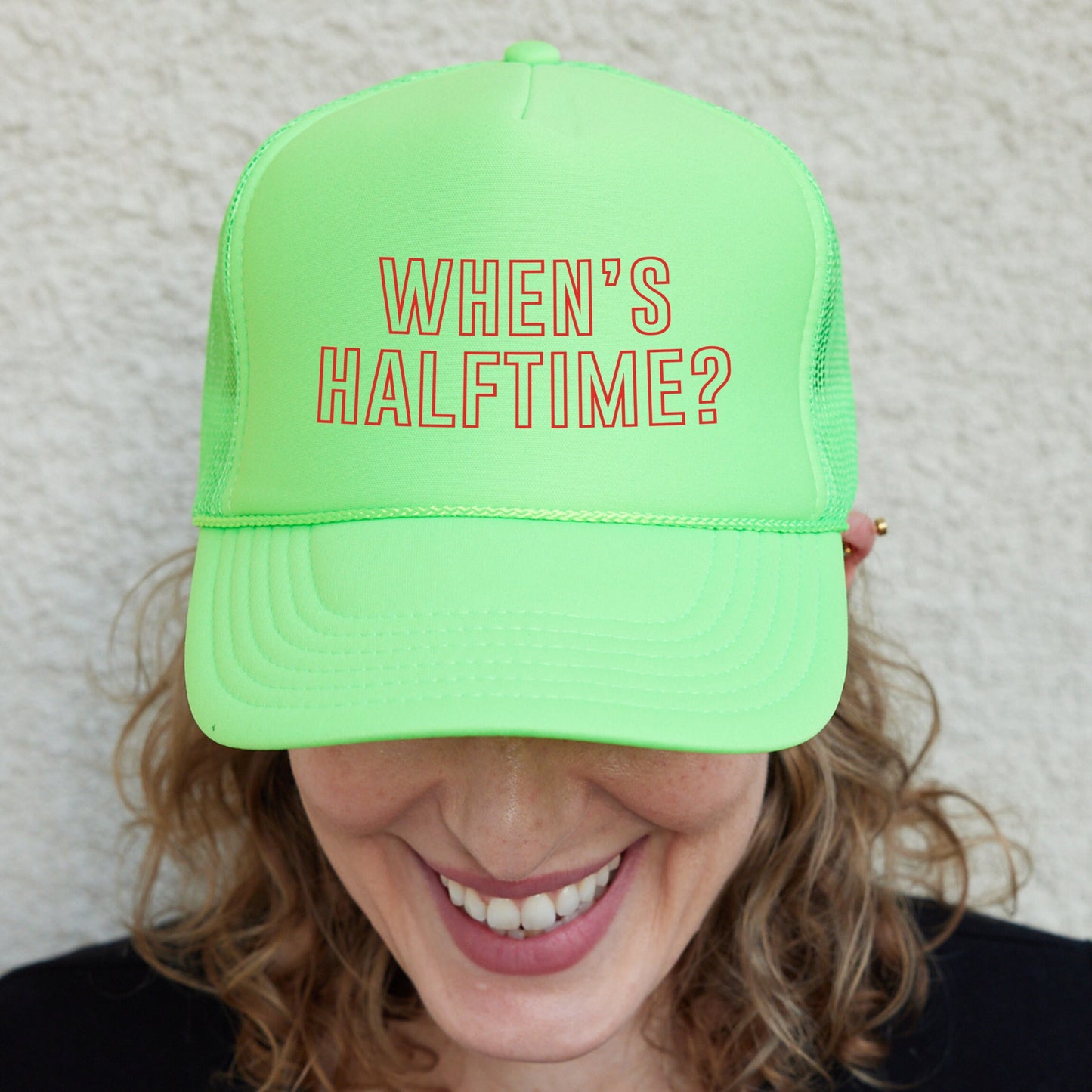 a woman wearing a neon green hat with the words when&#39;s half time?