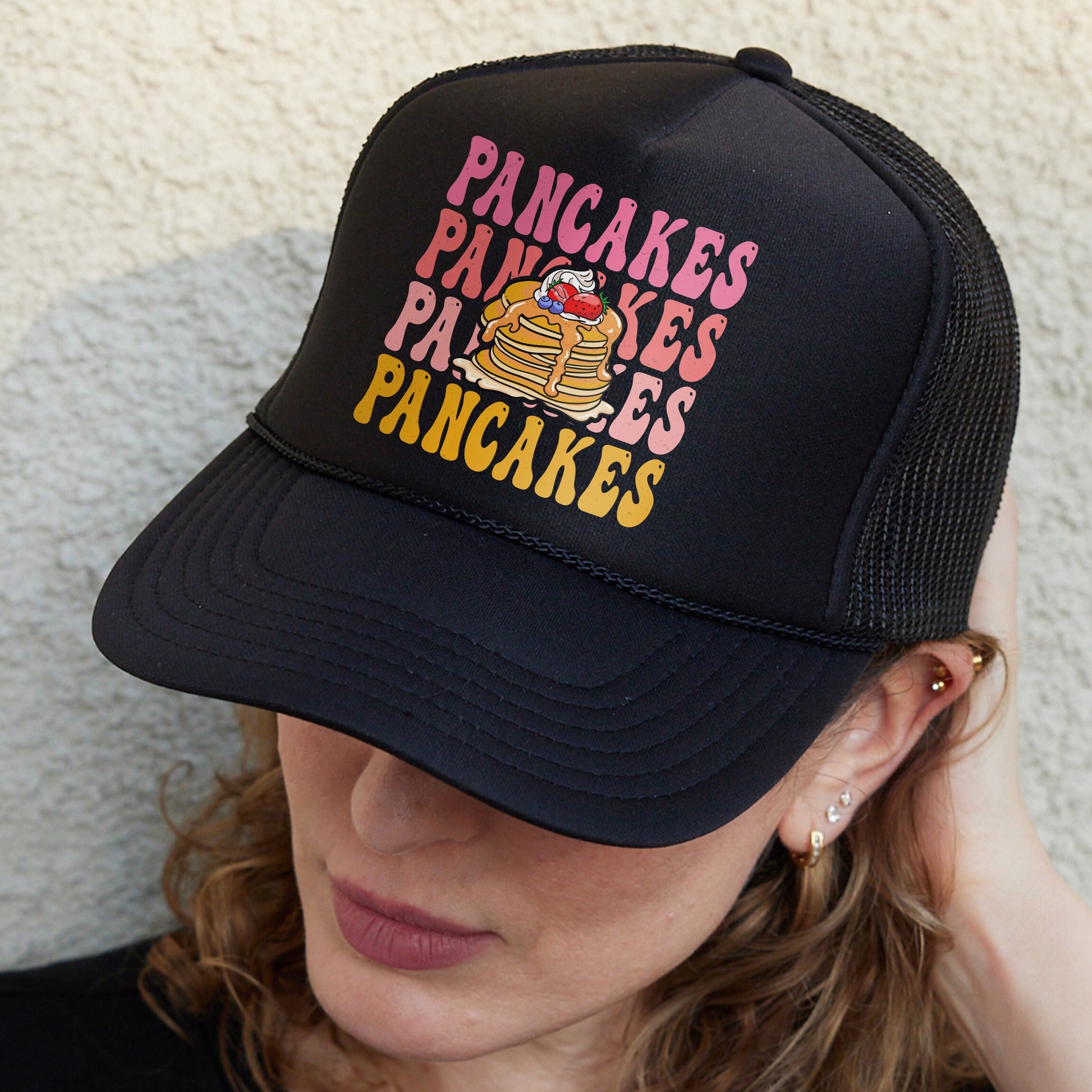 a woman wearing a black hat with a picture of pancakes on it