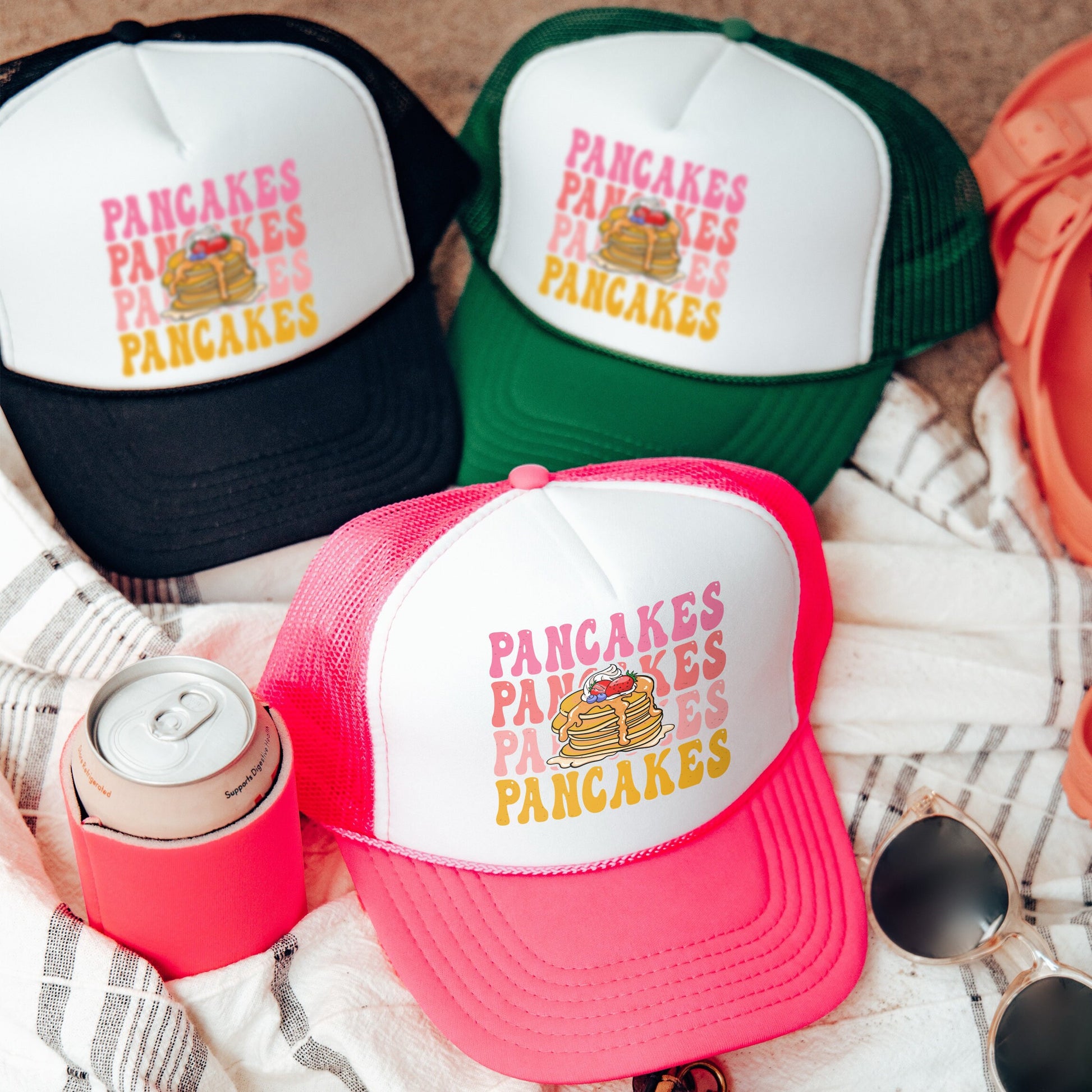three hats and sunglasses are laying on a blanket