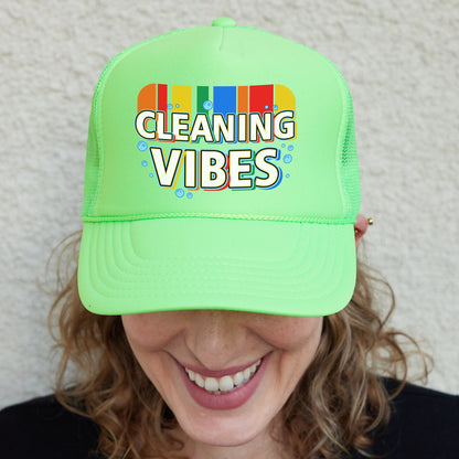 a smiling woman wearing a green cleaning vibes hat