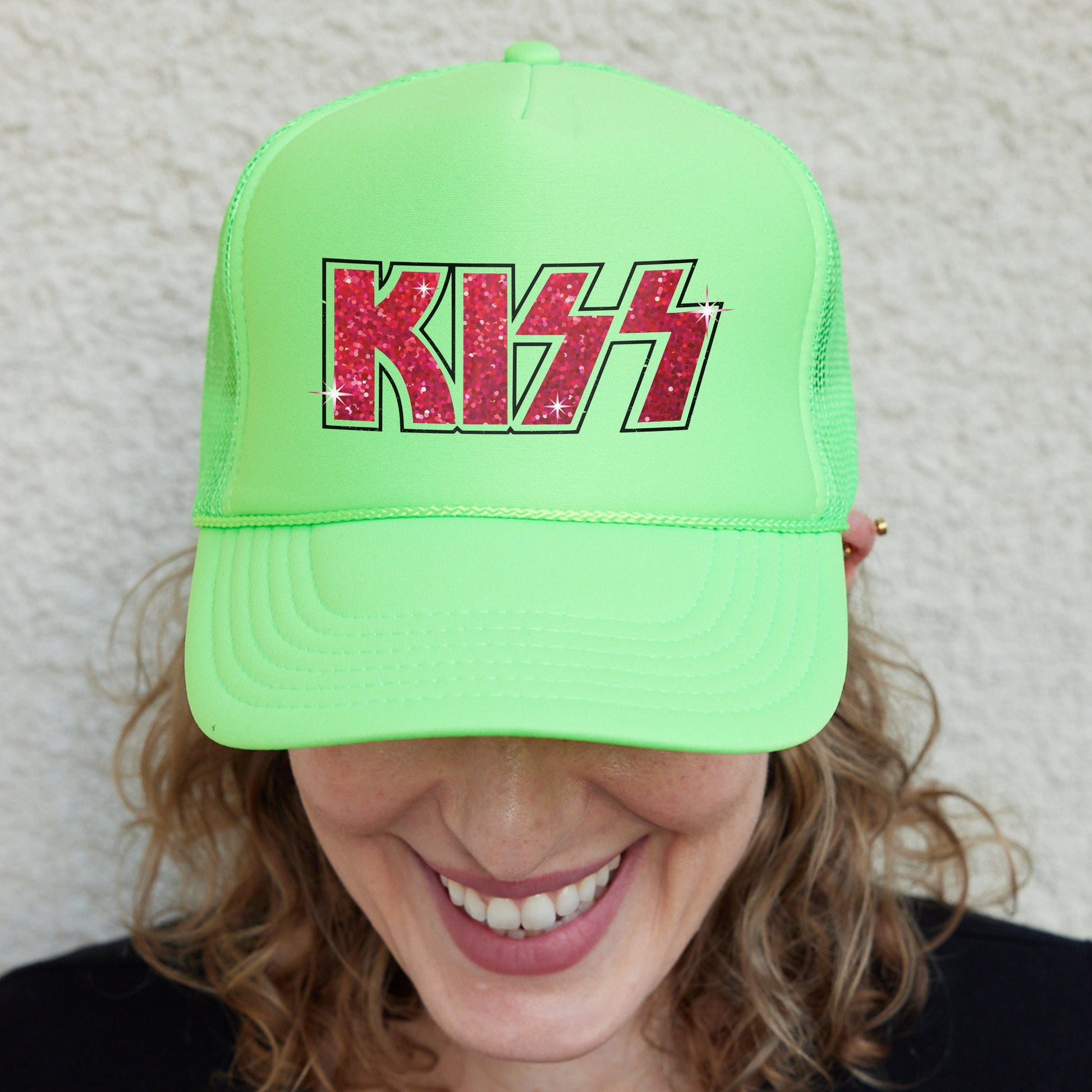 a woman wearing a green hat with the word kiss on it
