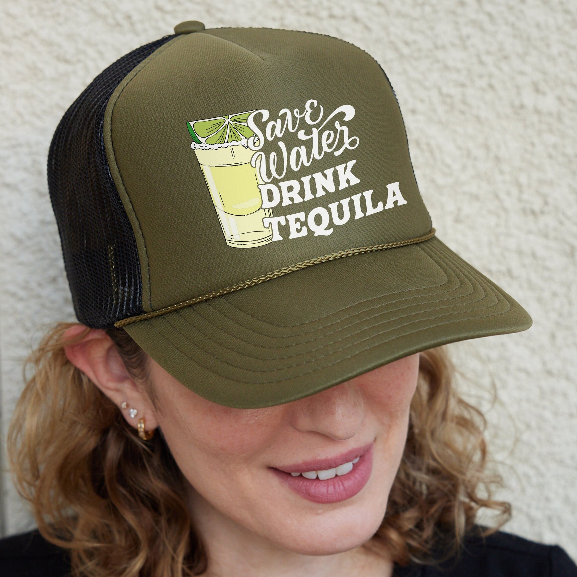 a woman wearing a trucker hat with a drink on it