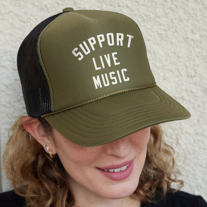 a woman wearing a trucker hat that says support live music