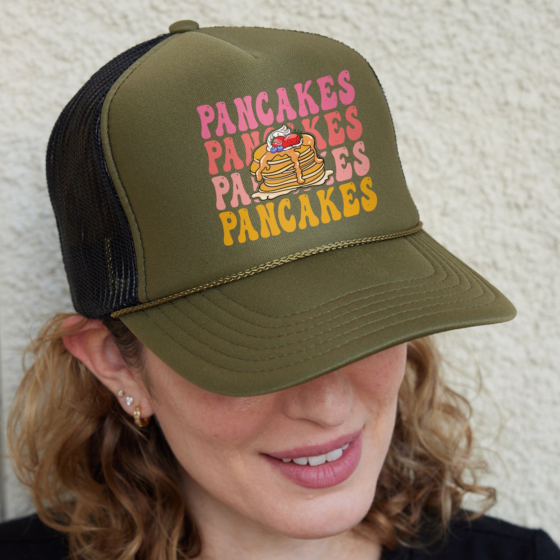 a woman wearing a green hat with a picture of a pancake on it