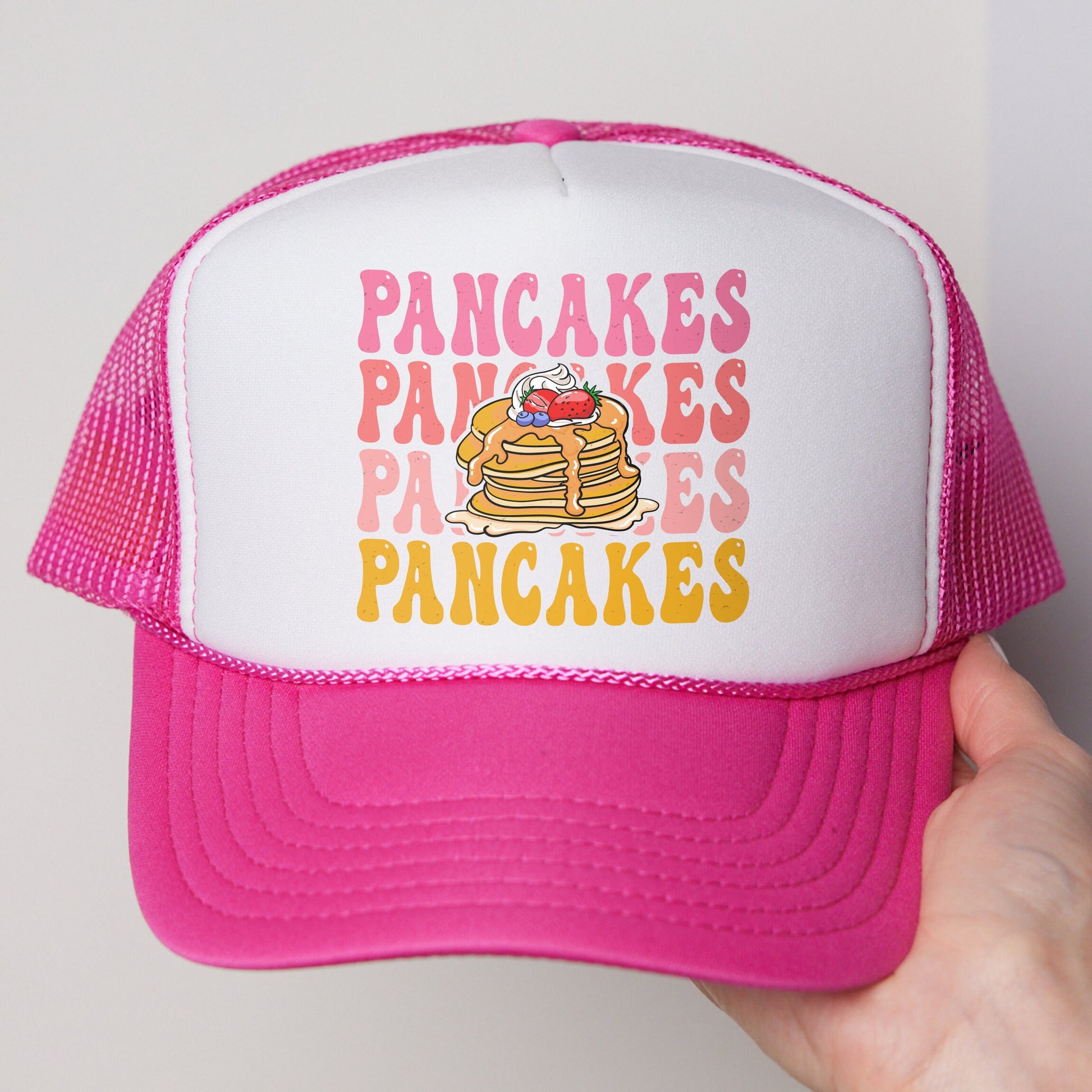 a person holding a pink and white trucker hat