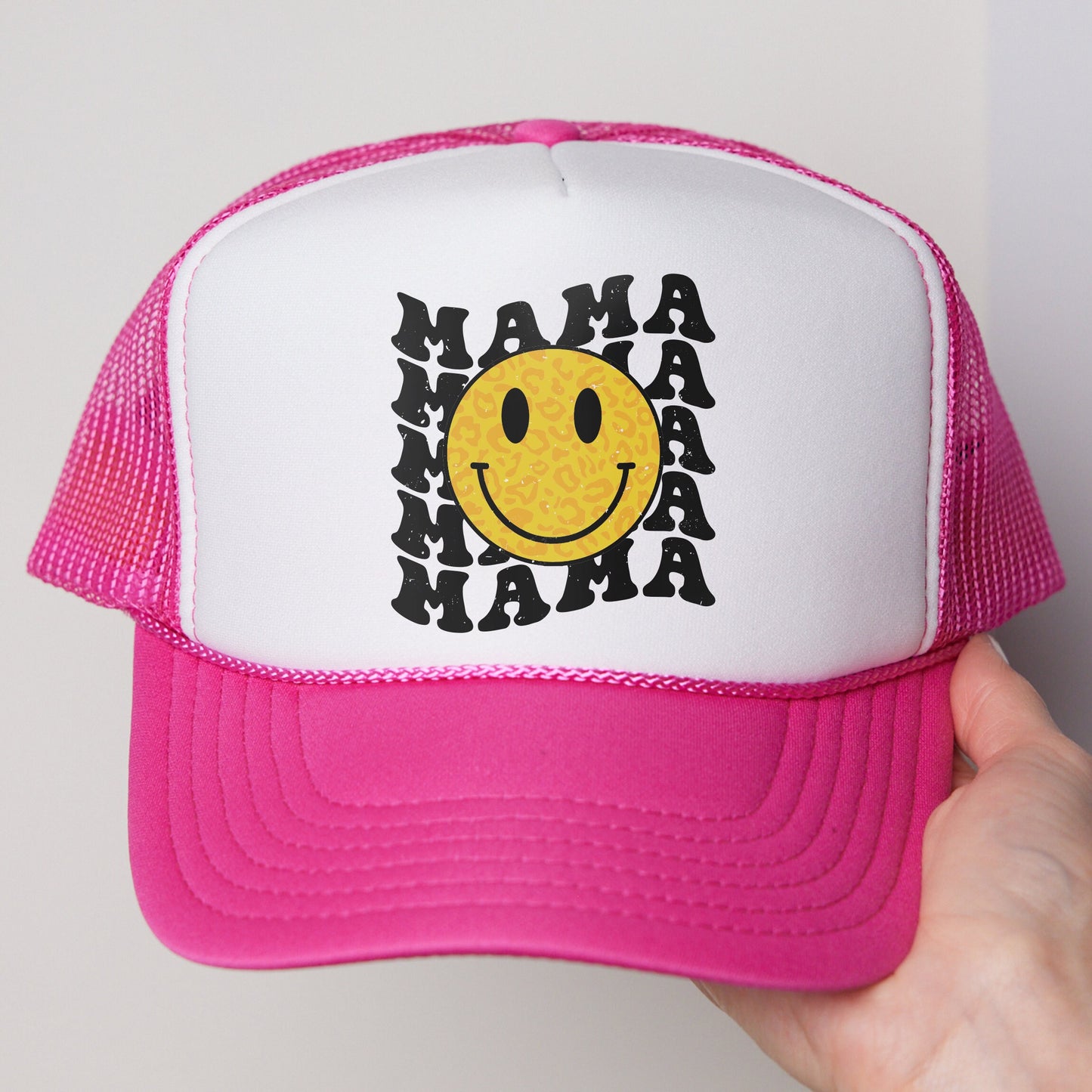 a pink and white trucker hat with a smiley face