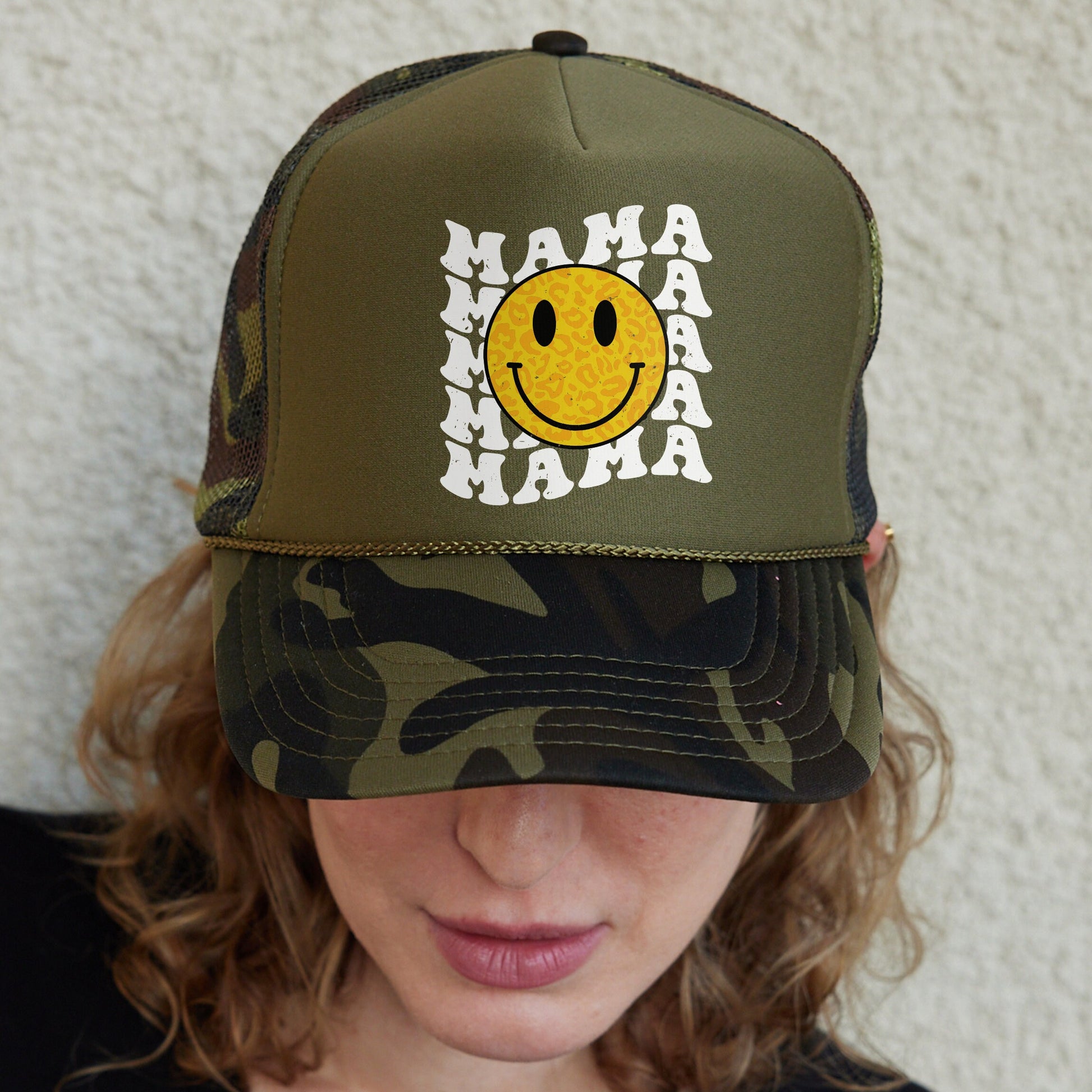 a woman wearing a camo hat with a smiley face on it