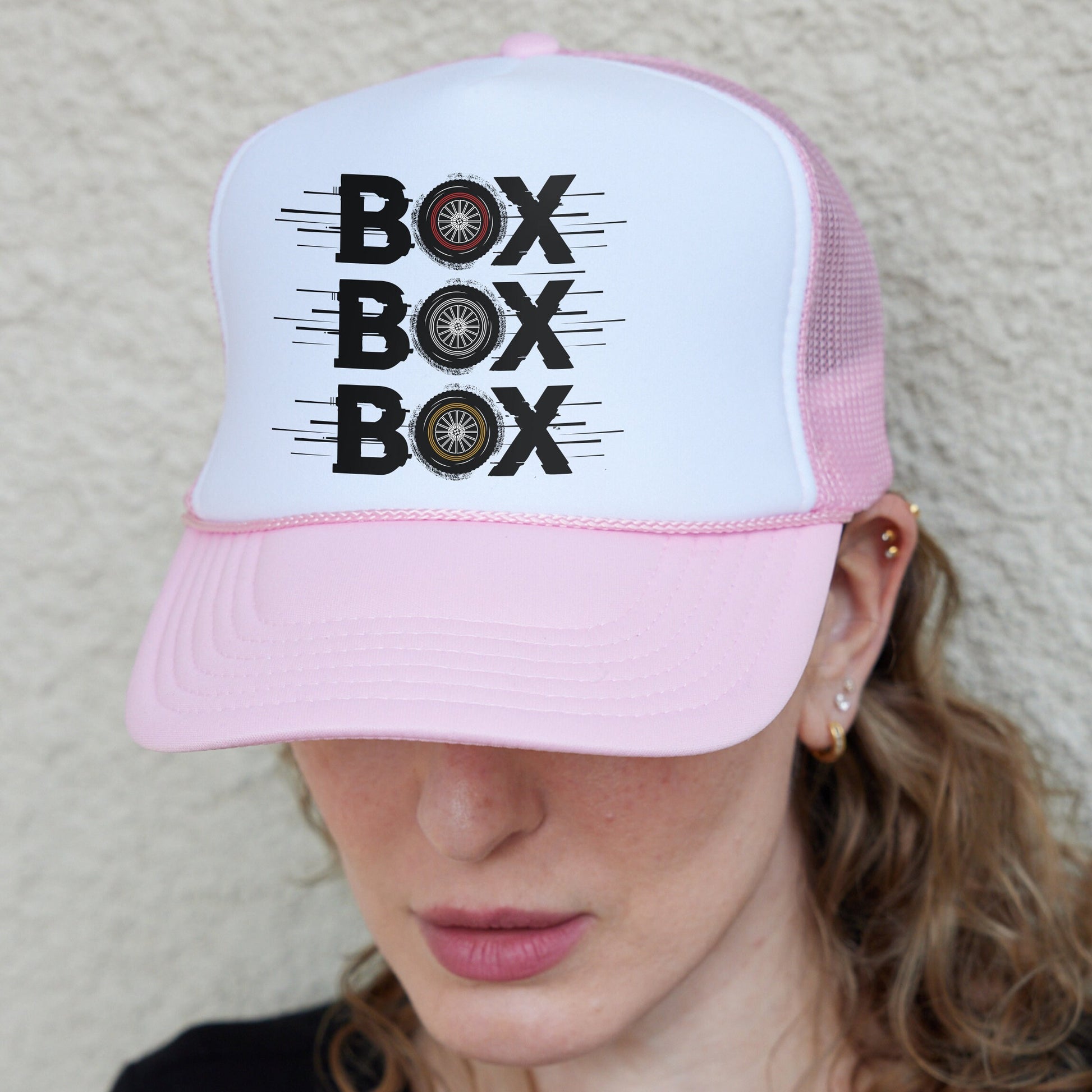 a woman wearing a pink and white hat with the words box box on it