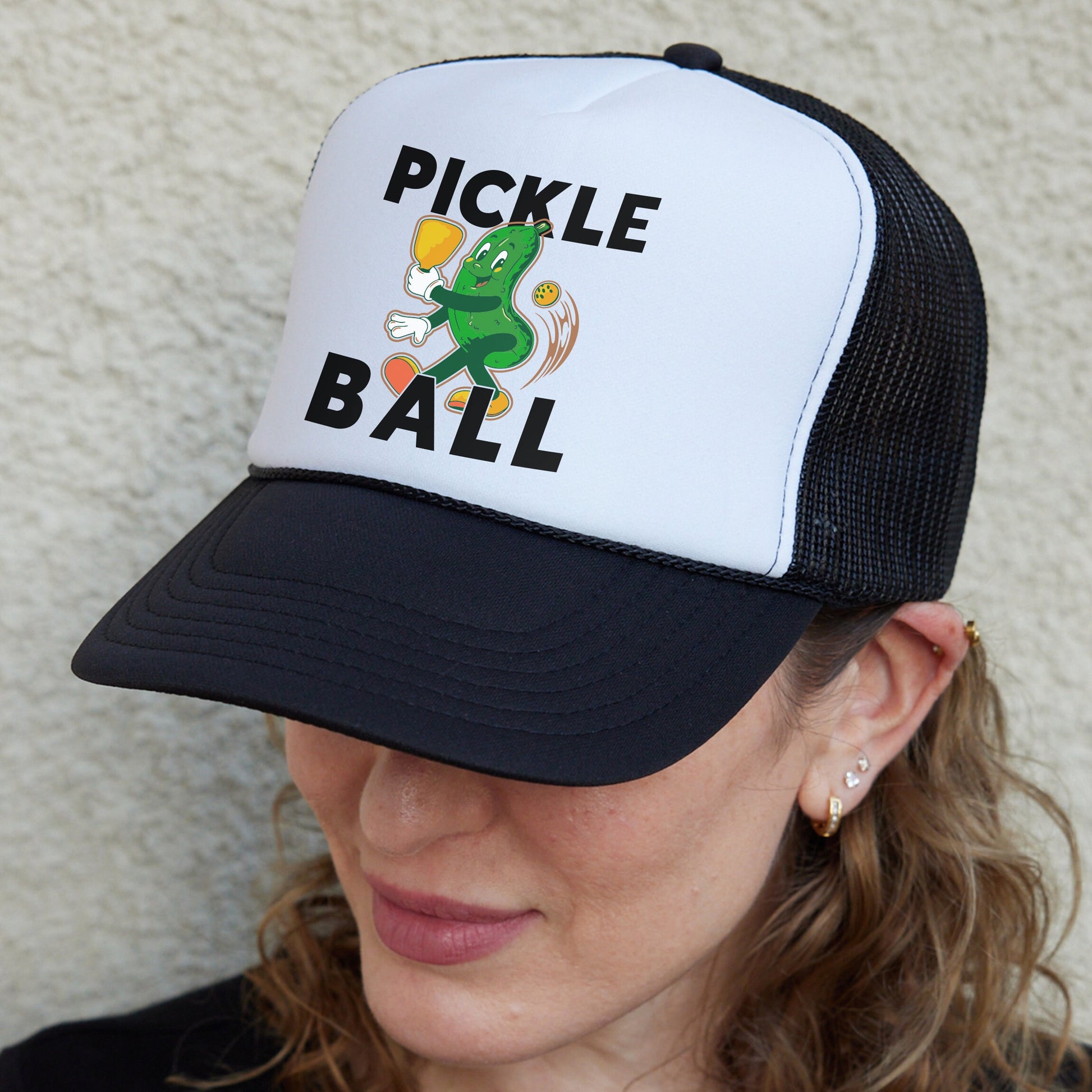 a woman wearing a trucker hat with a pickle ball on it