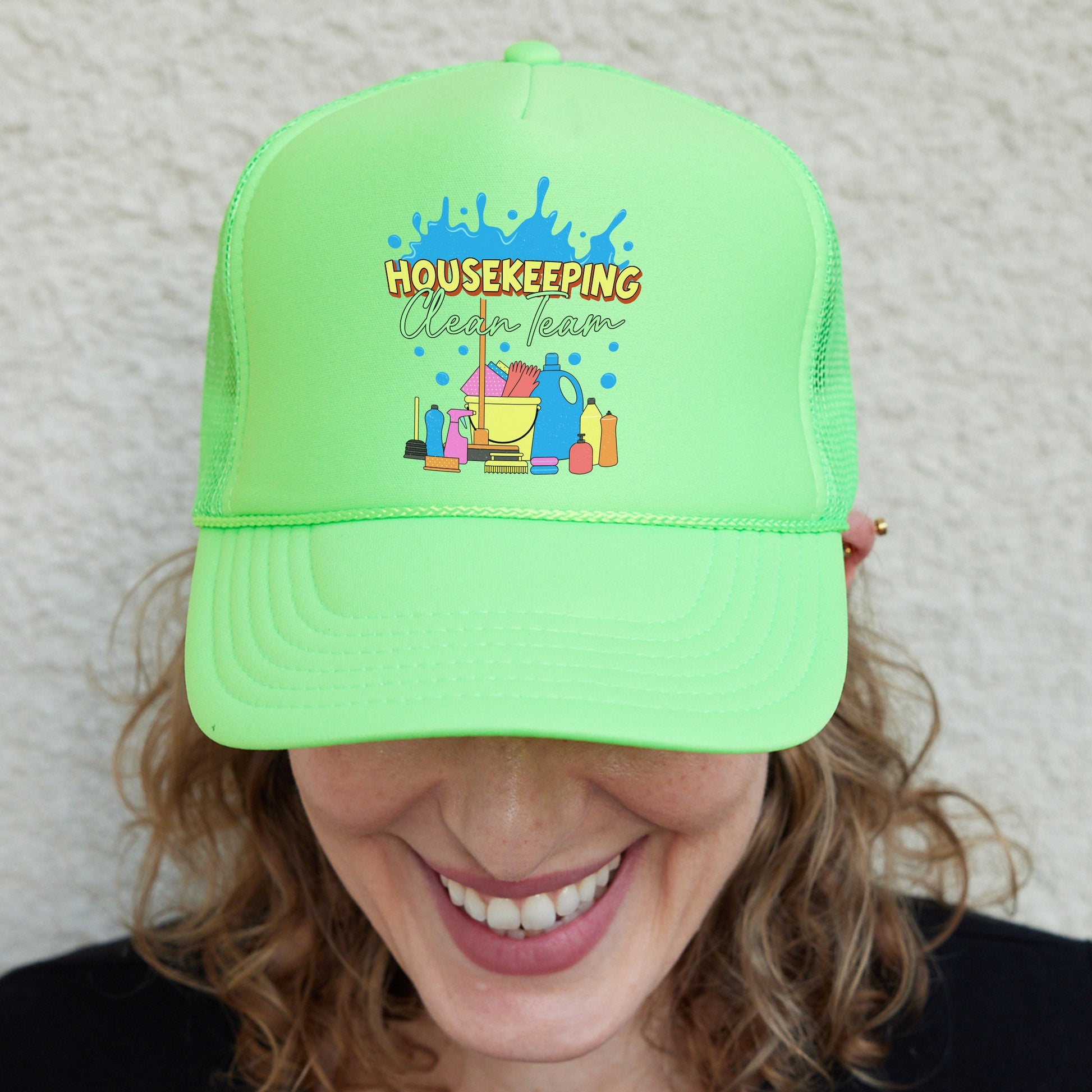 a woman wearing a green trucker hat with the words housekepping on it