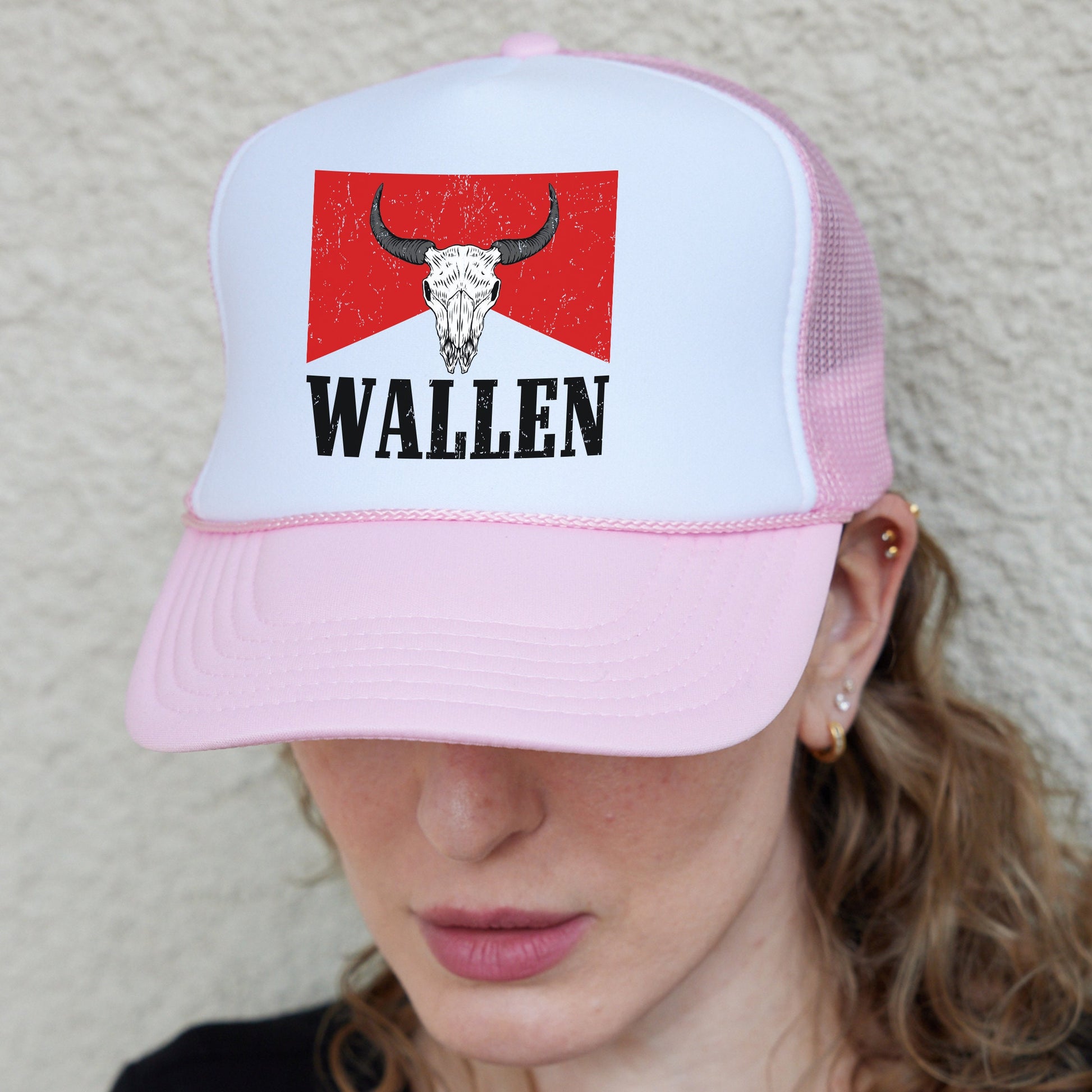 a woman wearing a pink and white hat with a bull&#39;s head on it