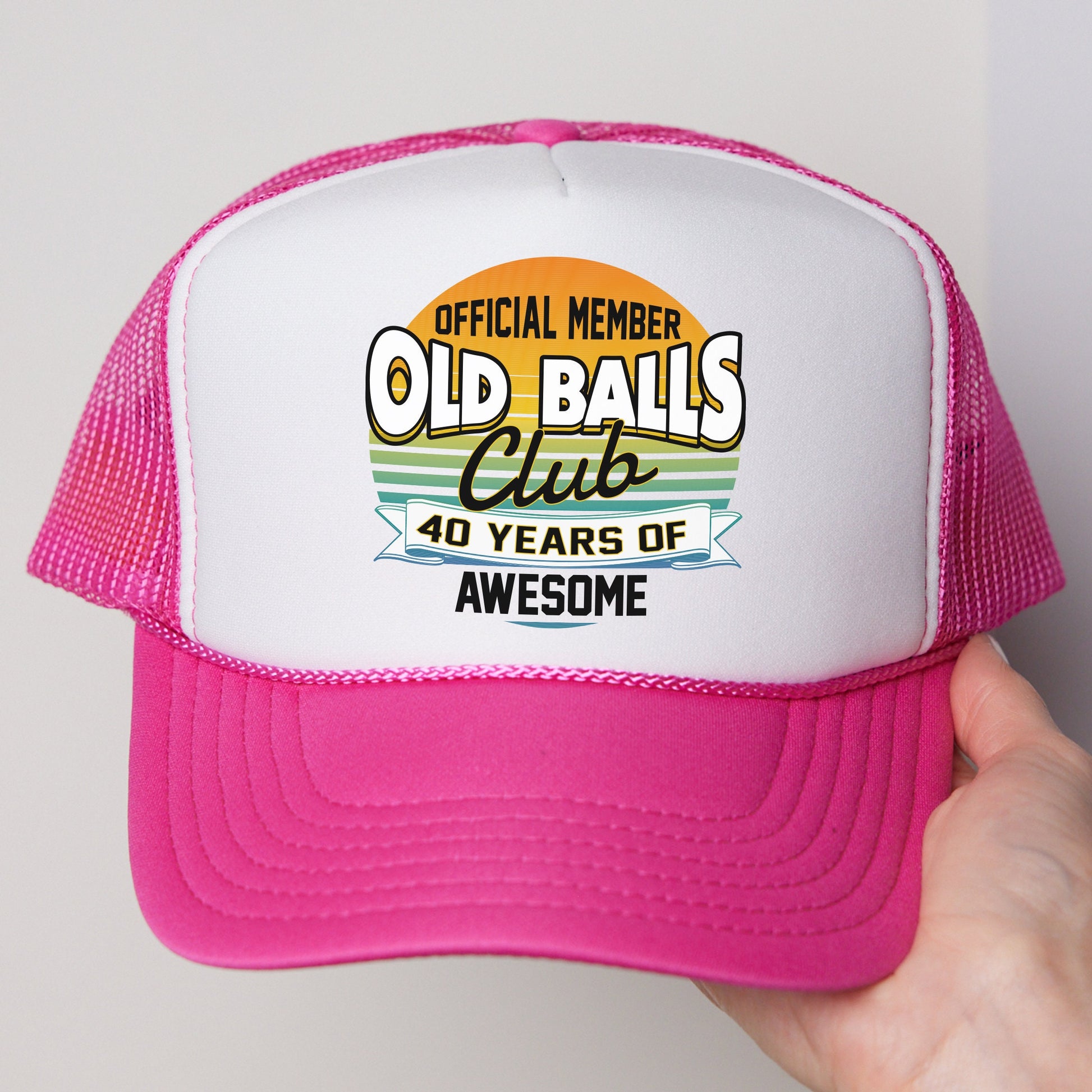 a person holding a pink and white trucker hat