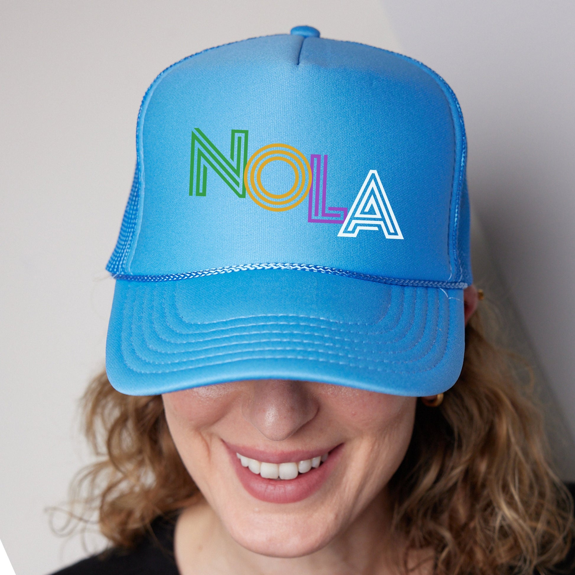 a woman wearing a blue hat with the word nola painted on it