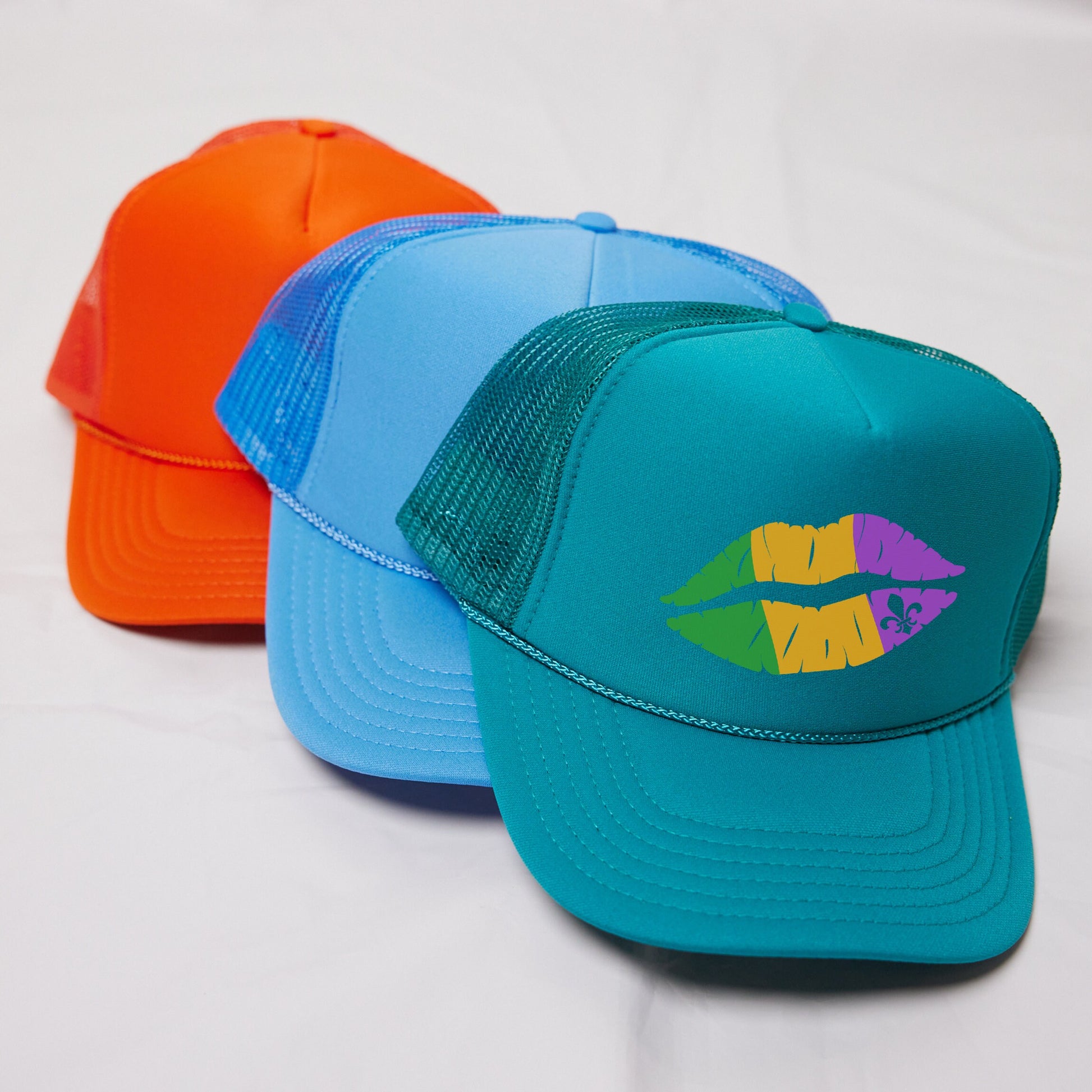 three different colored hats on a white surface