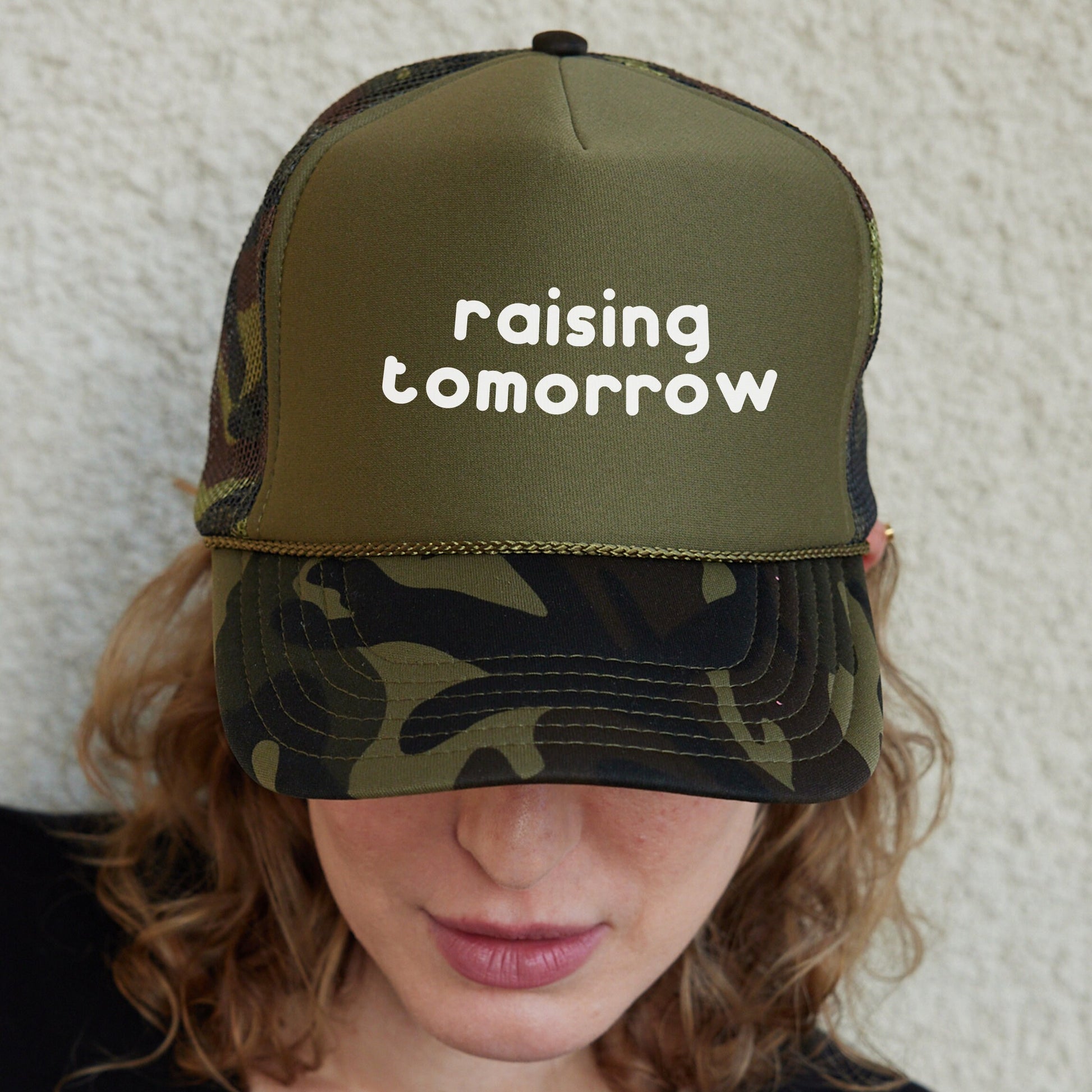 a woman wearing a hat with the words raising tomorrow written on it