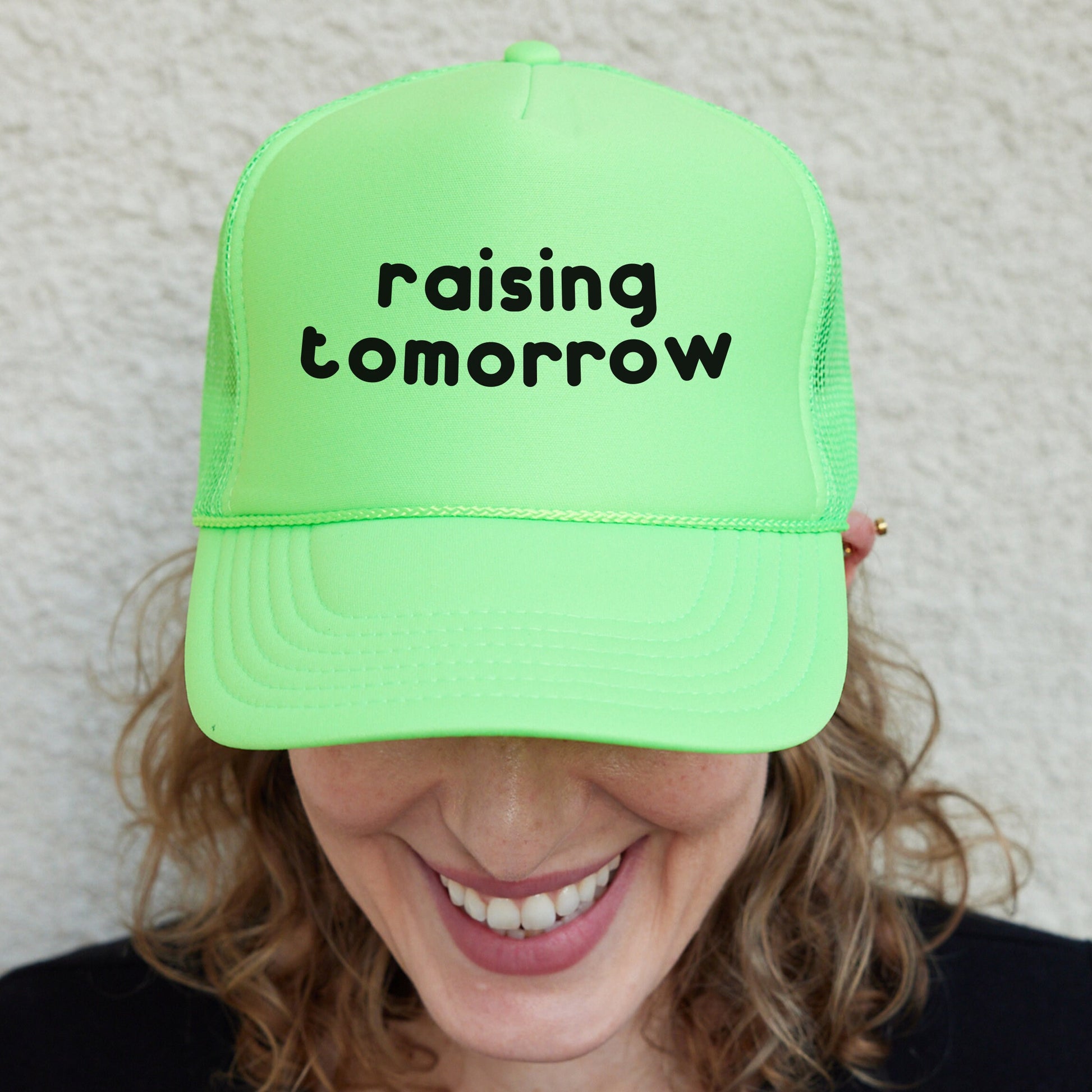 a woman wearing a neon green hat that says raising tomorrow