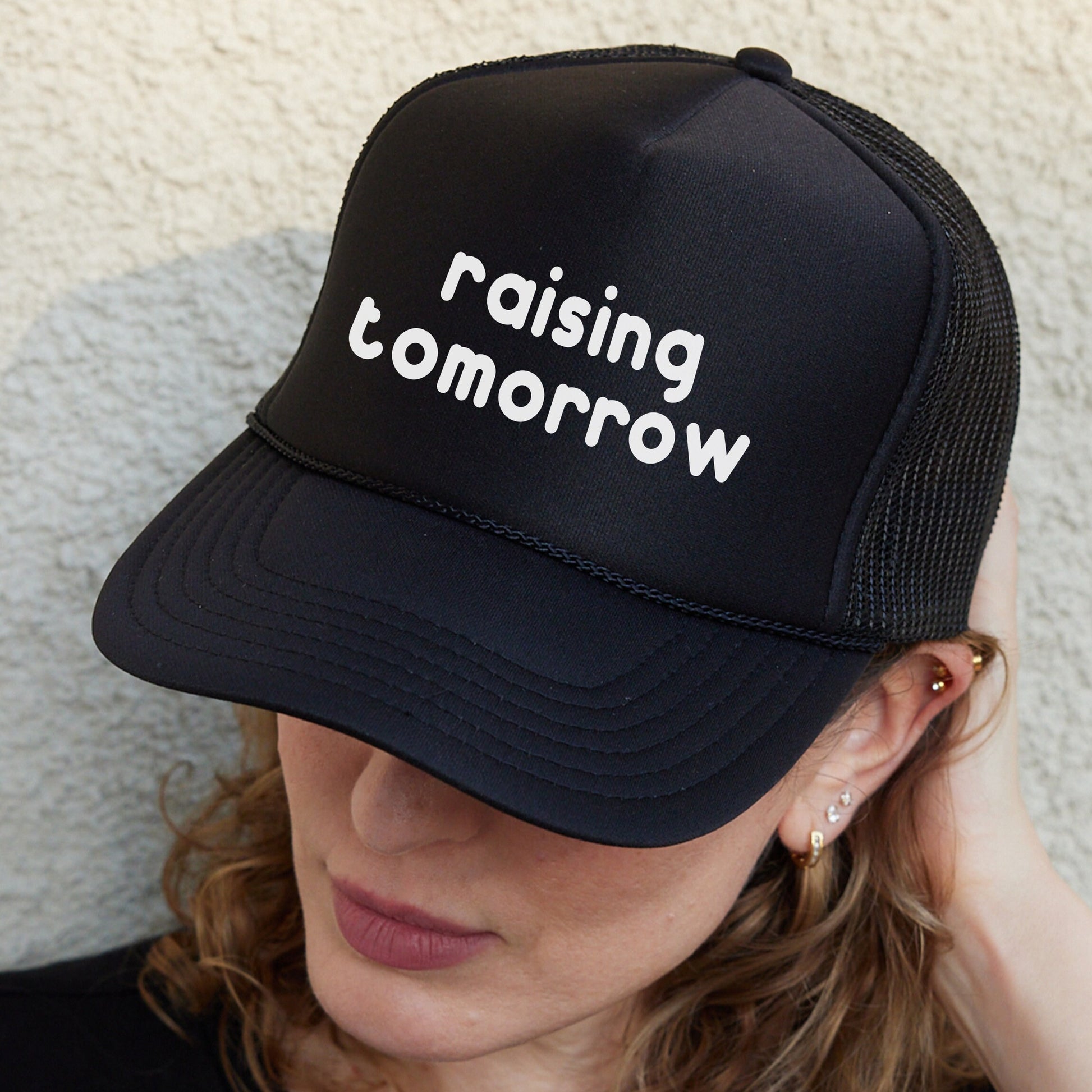 a woman wearing a black hat that says raising tomorrow