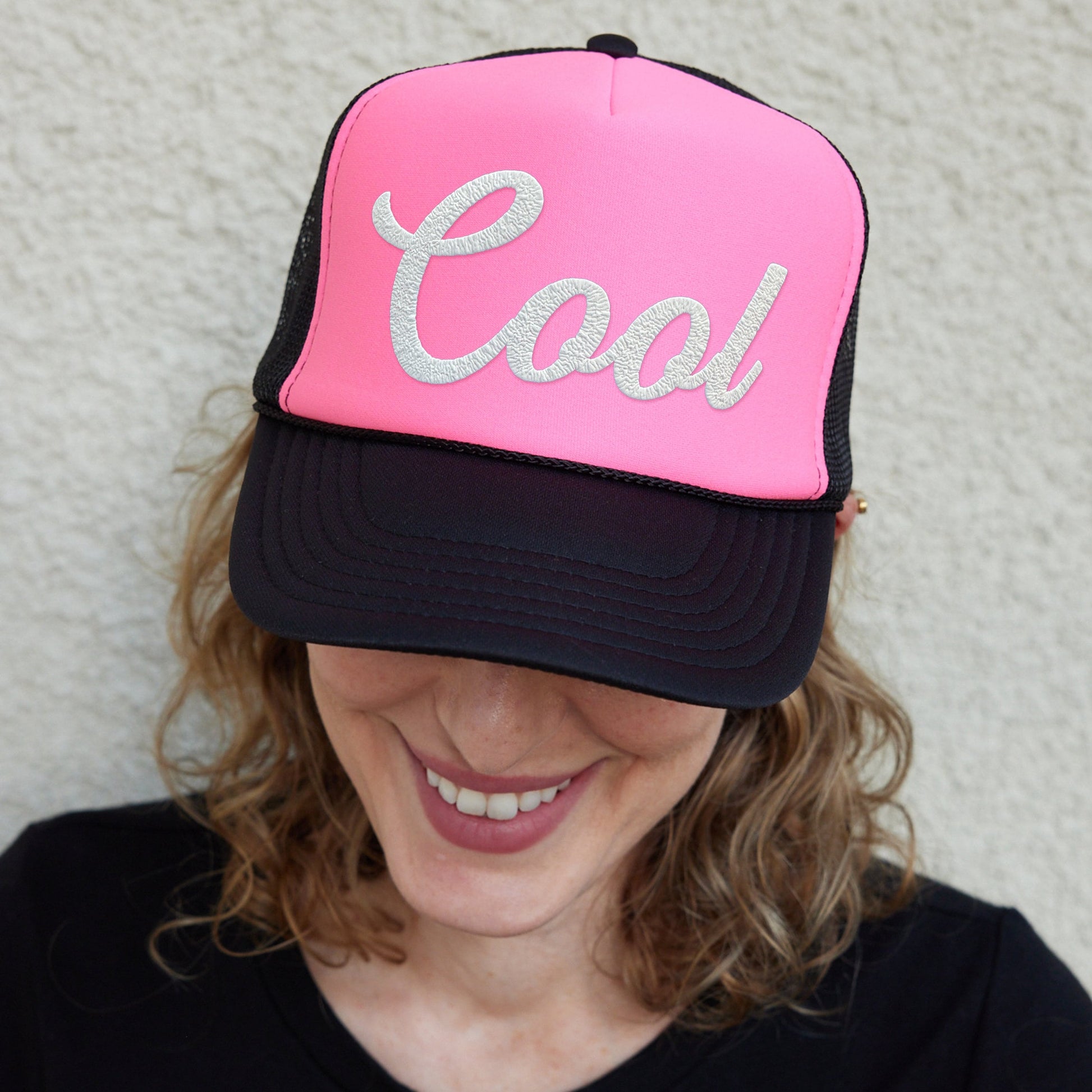a woman wearing a pink and black hat with the word cool on it