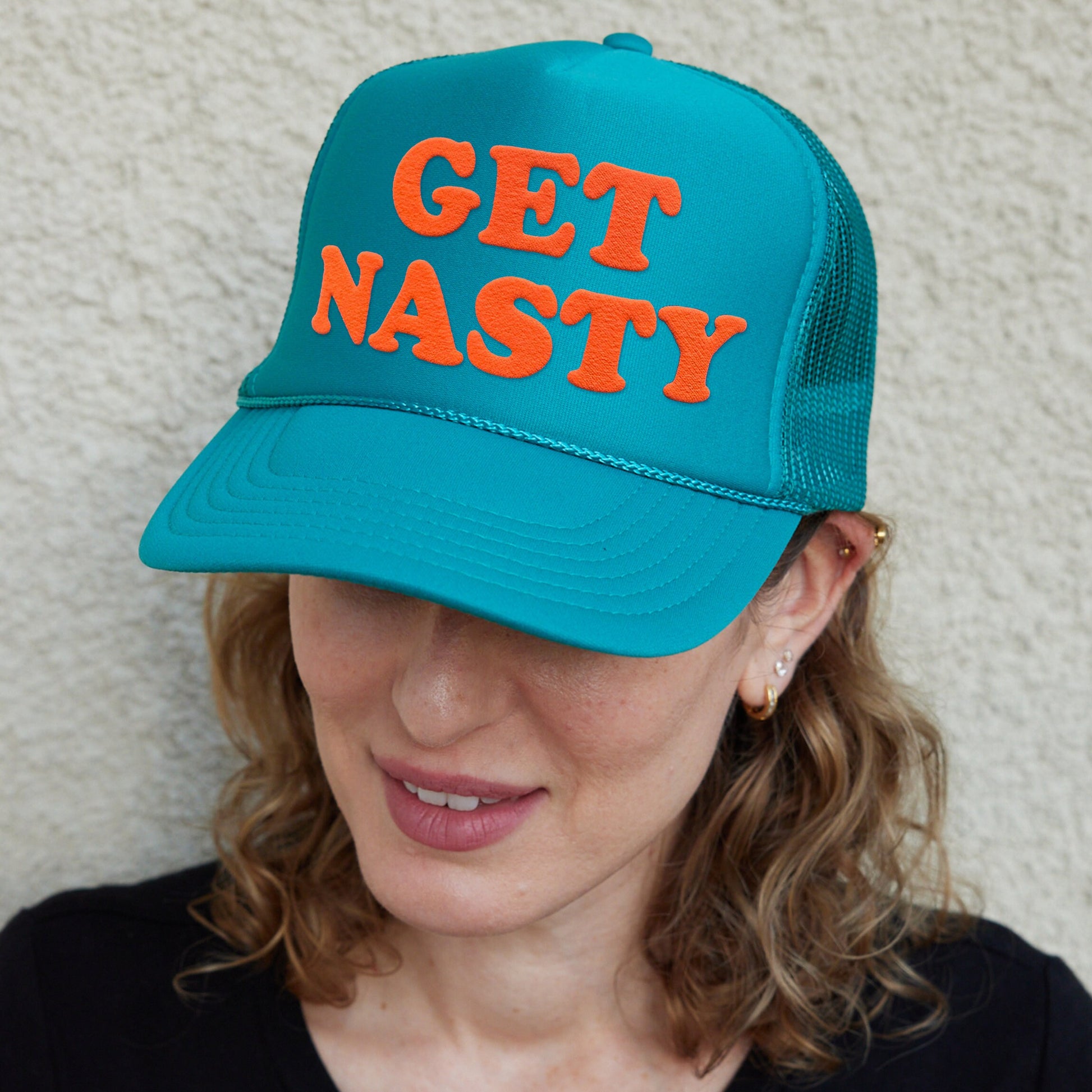 a woman wearing a turquoise hat with orange lettering