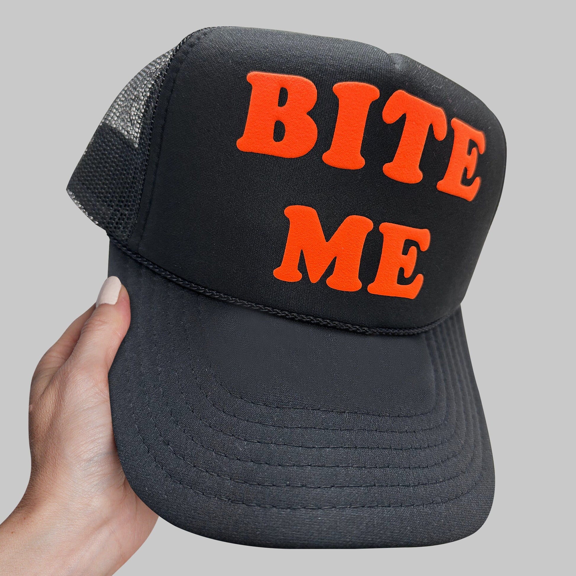 a person holding up a black and orange hat