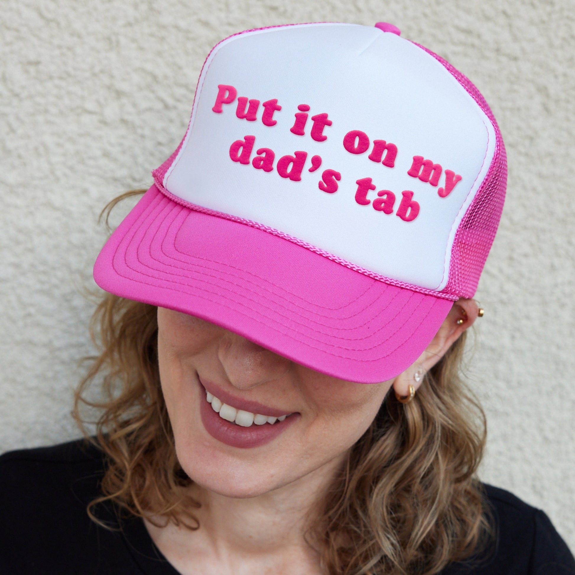 a woman wearing a pink and white hat with the words put it on my dad