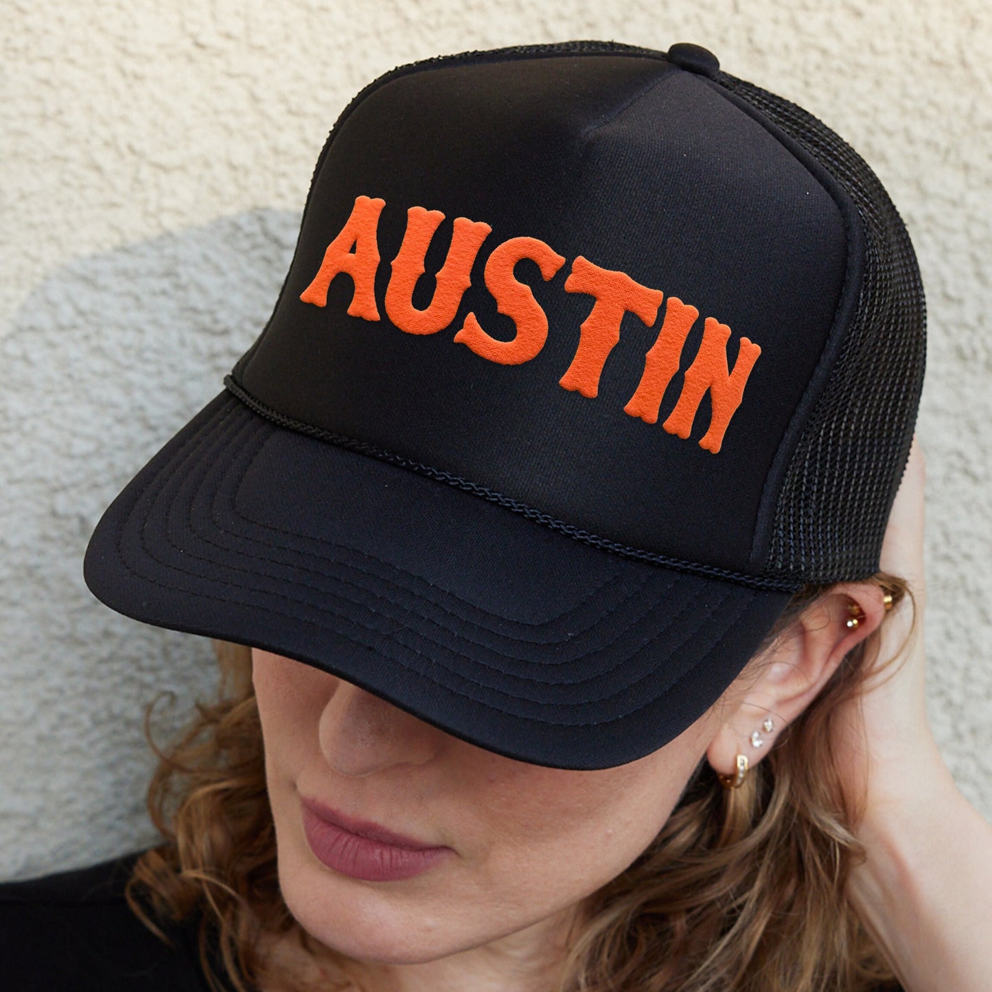 a woman wearing a black hat with an orange word on it